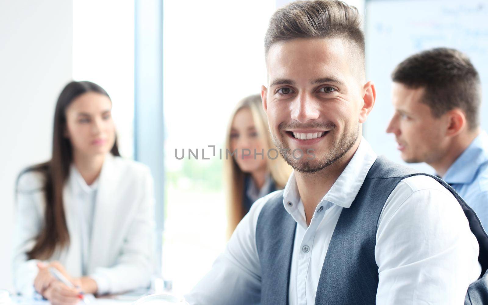 Businessman with colleagues in the background in office.