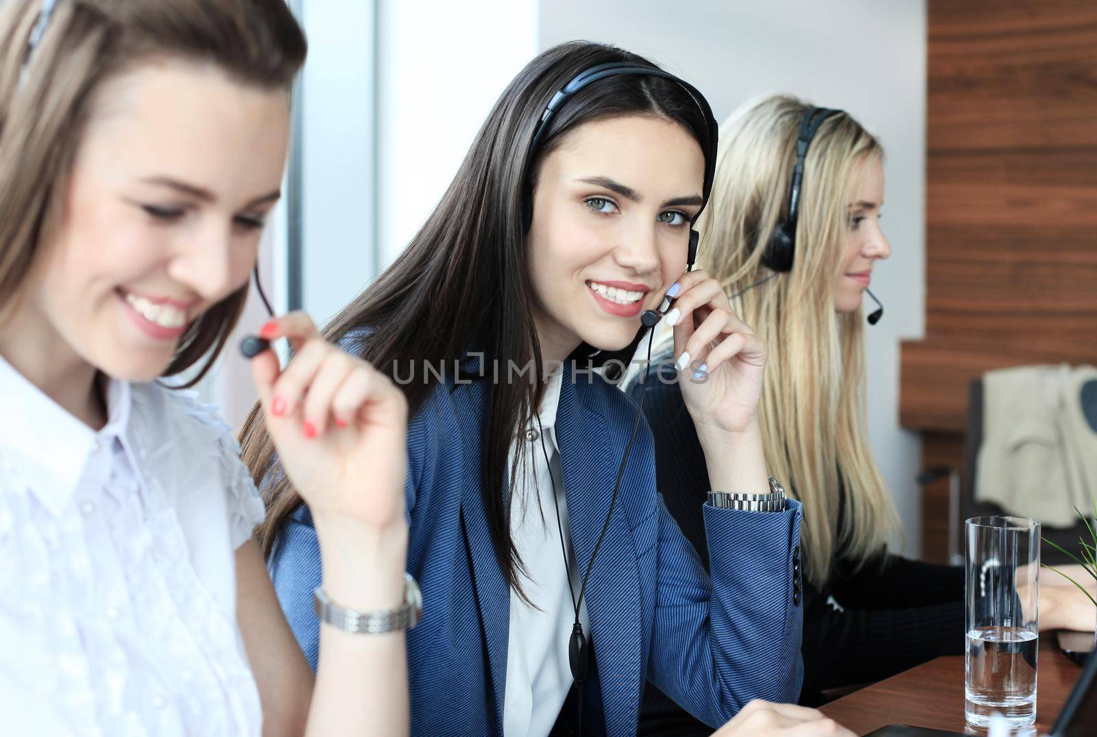Portrait of call center worker accompanied by her team. Smiling customer support operator at work. by tsyhun