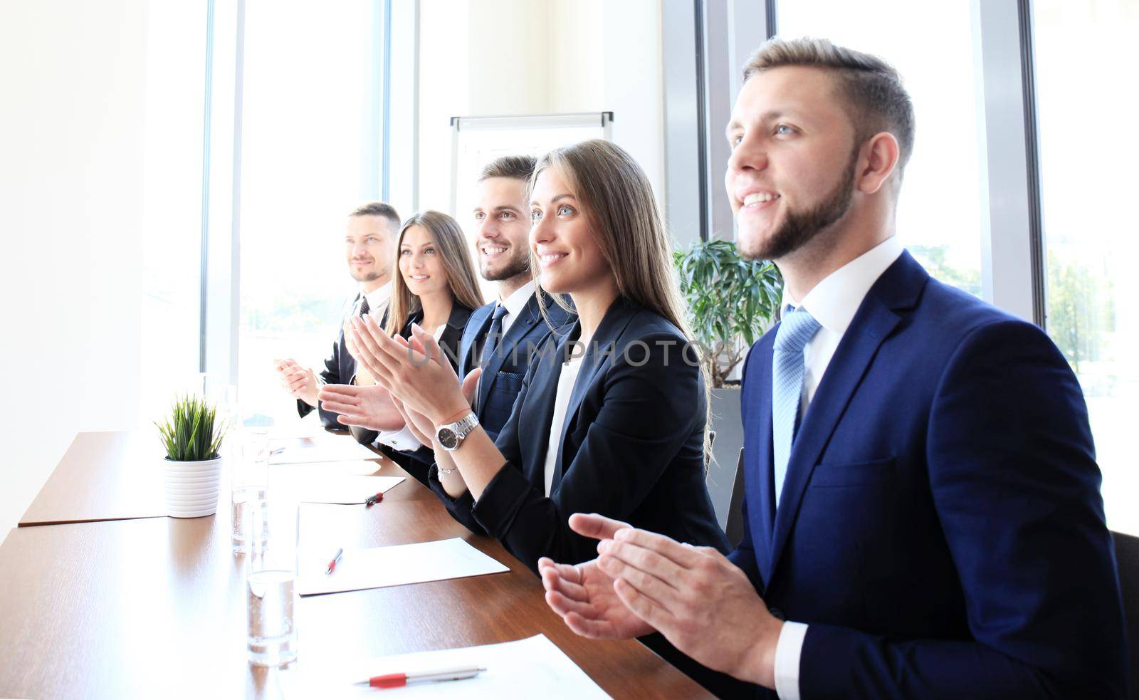 Photo of happy business people applauding at conference, focus on smiling girl