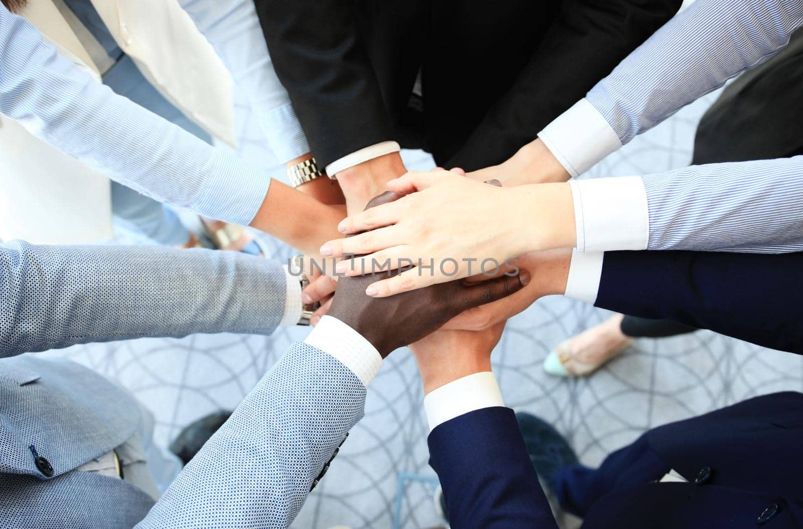 Multiethnic group of young people putting their hands on top of each other. Close up image of young business people making a stack of hands.