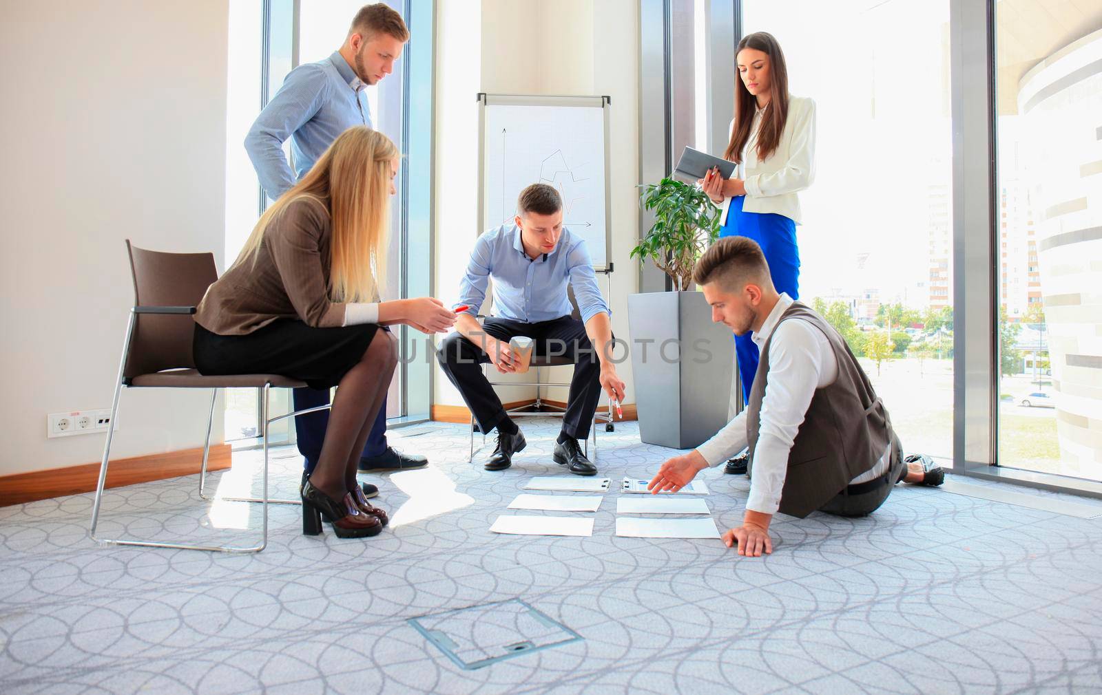 Creative people looking at project plan laid out on floor. Business associates discussing project plan in modern office. by tsyhun