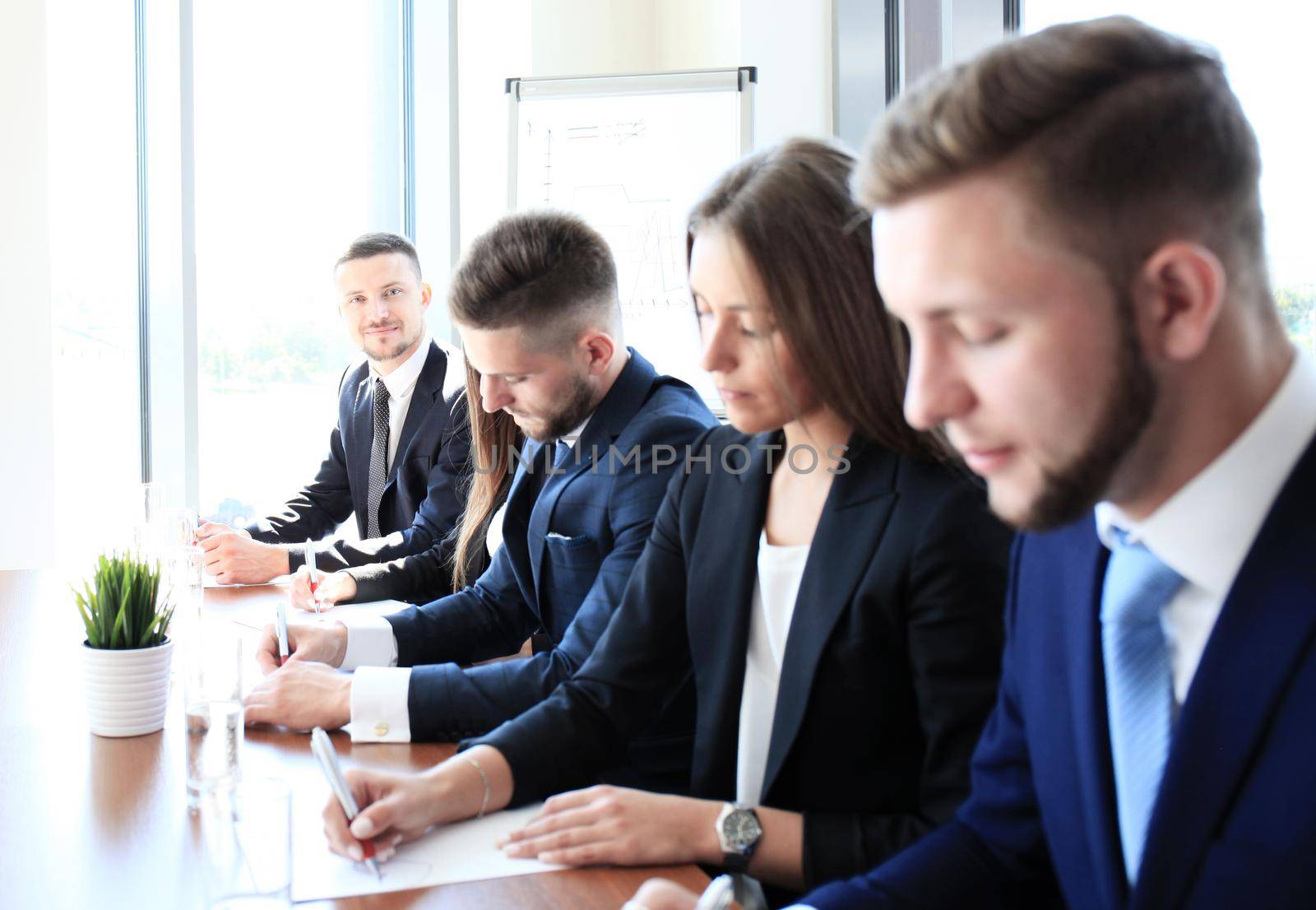 Smiling businesswoman looking at camera at seminar with her colleagues near by by tsyhun