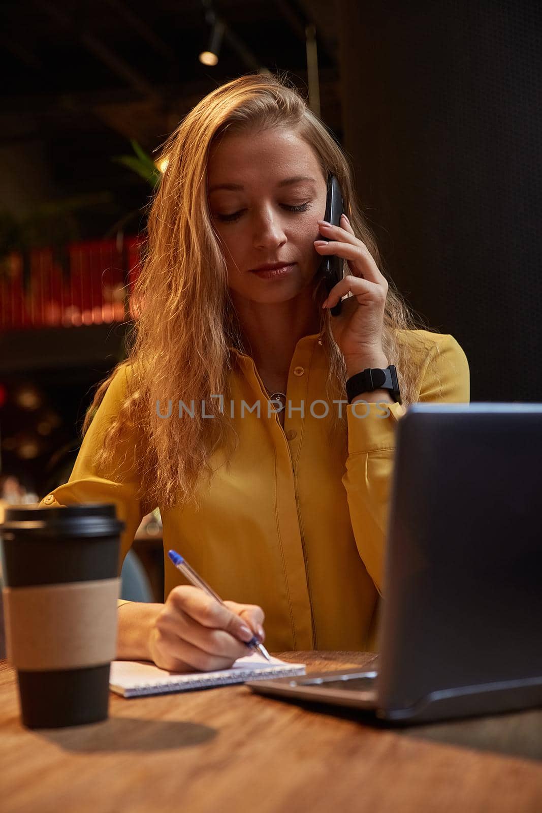 young well dressed cauasian woman sitting at coffee shop, calling by smartphone by artemzatsepilin