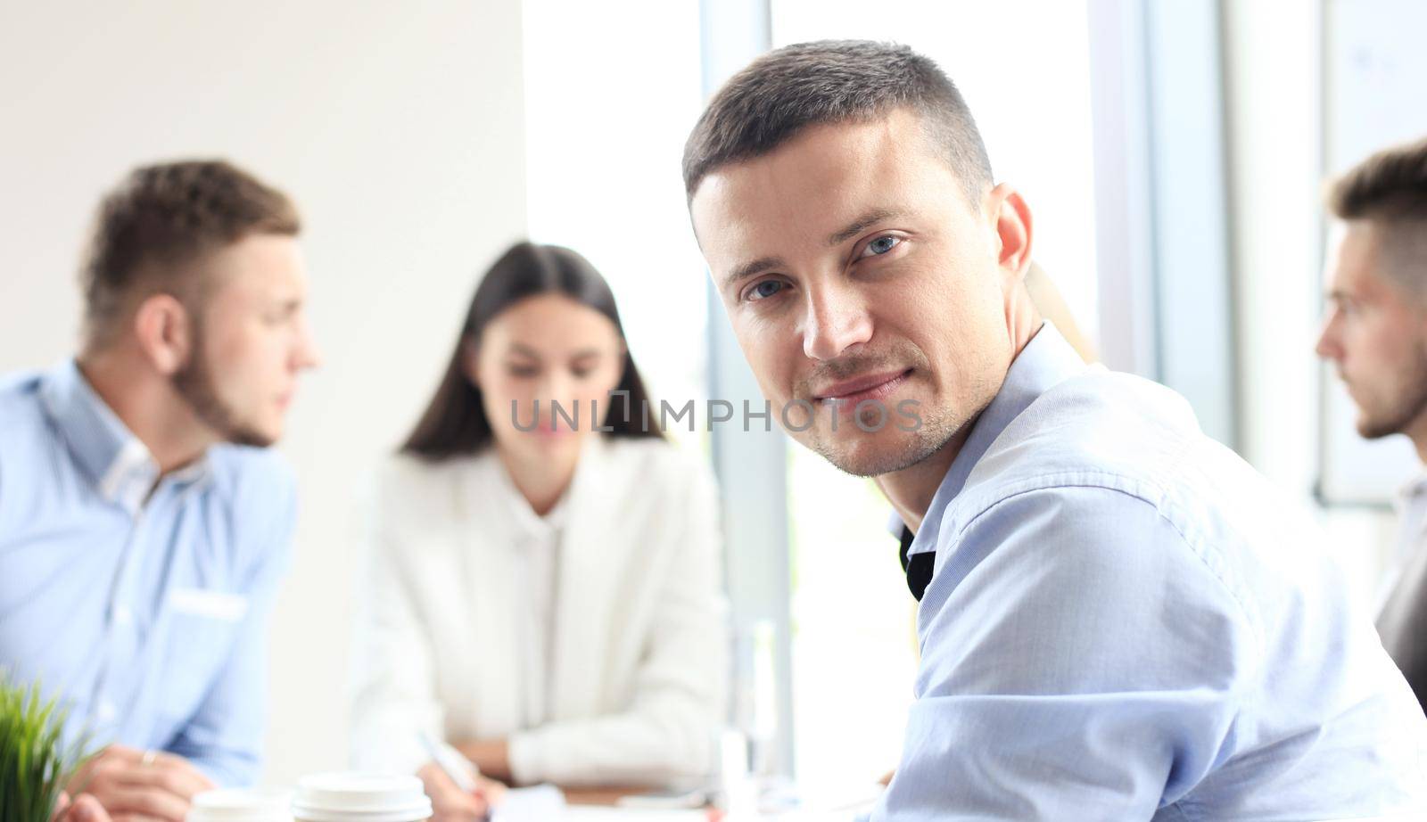 Businessman with colleagues in the background in office. by tsyhun