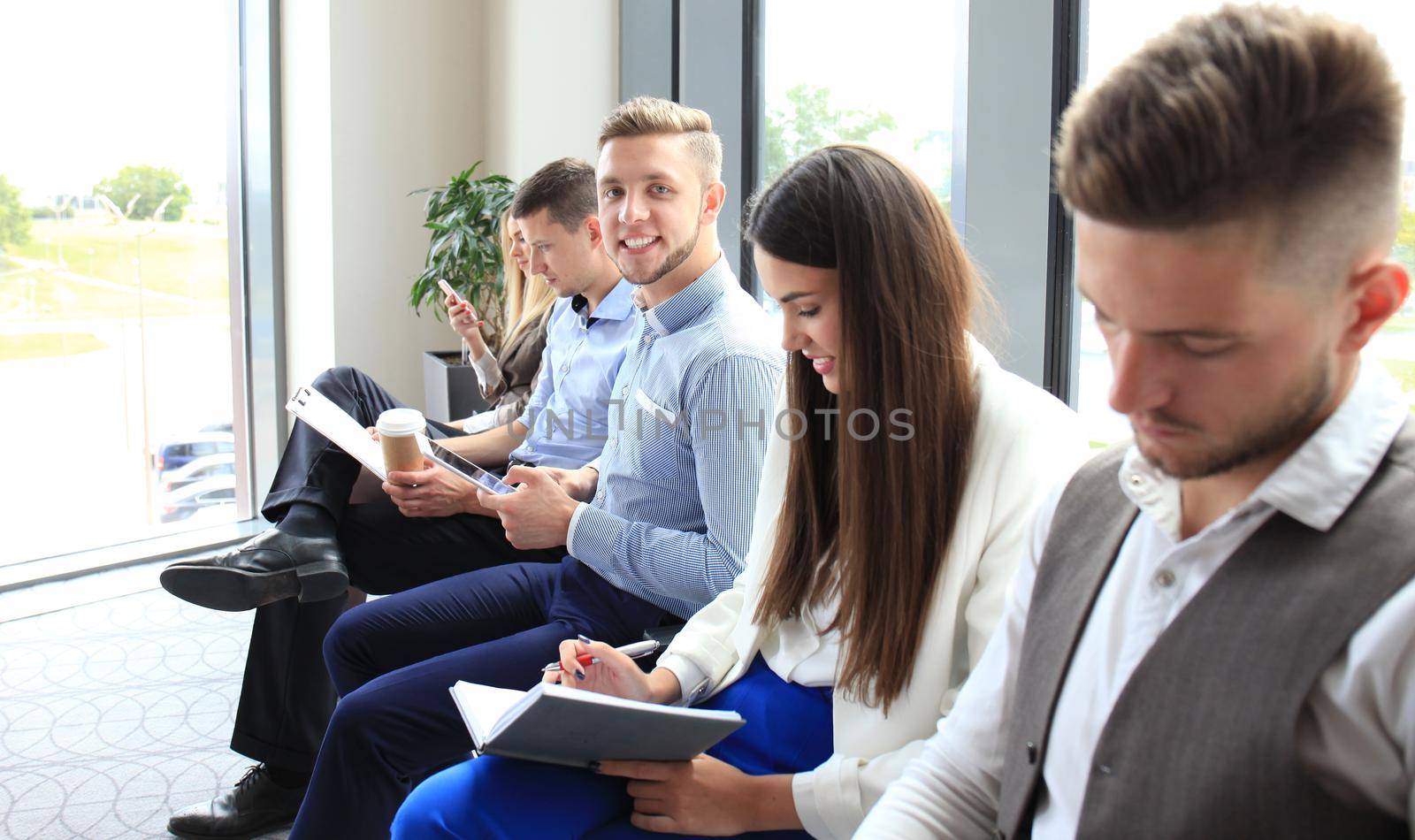 Smiling businessman looking at camera at seminar with her colleagues near by