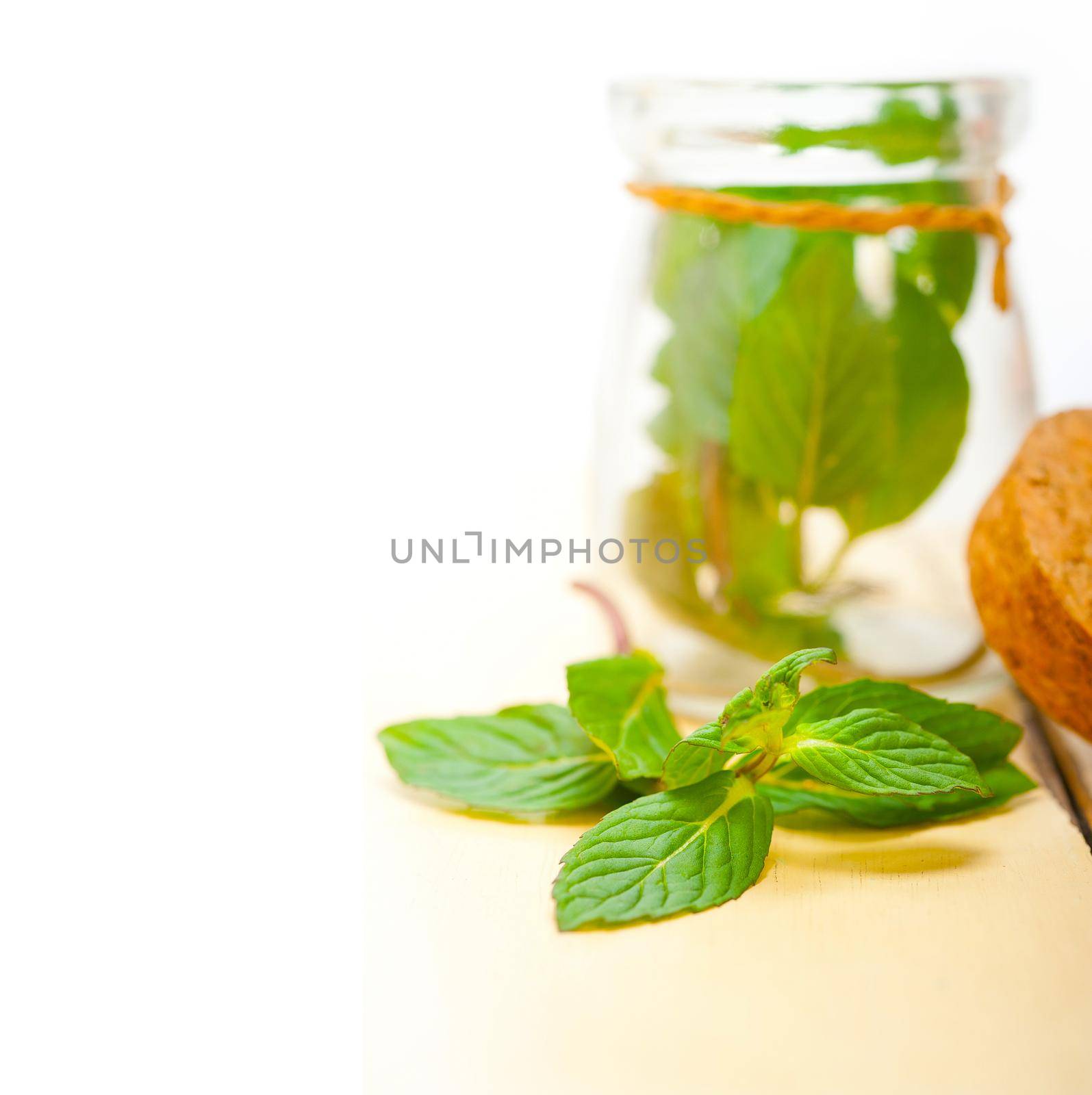 fresh mint leaves on a glass jarover a rustic white wood table