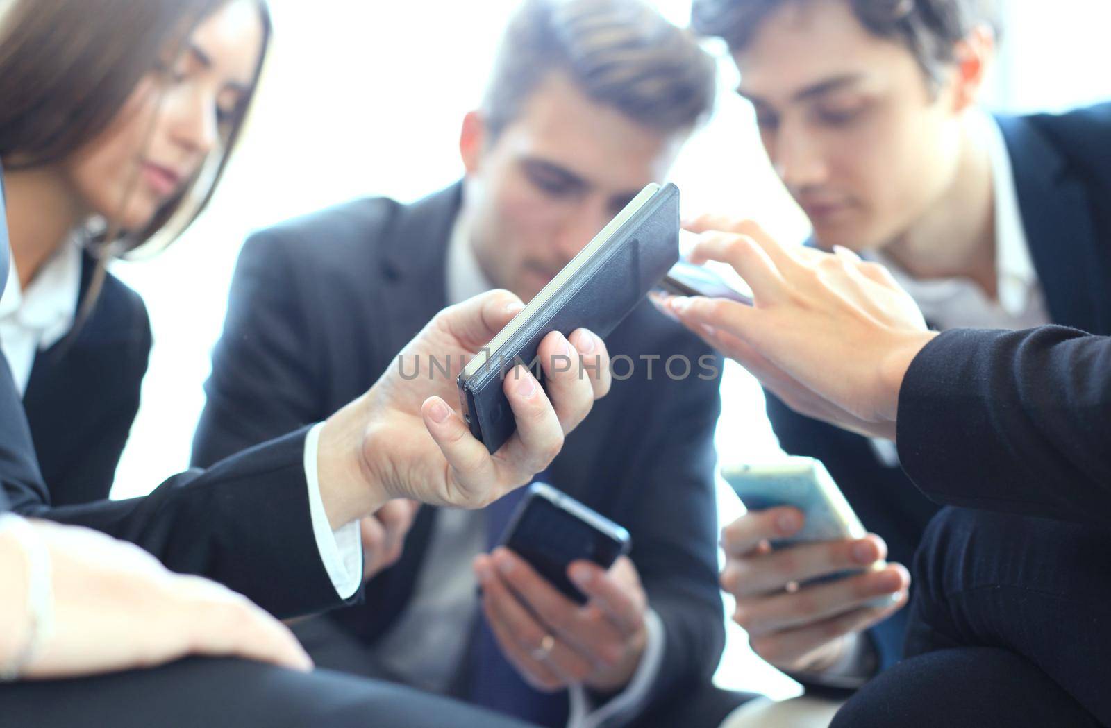 Group of people using smart phones sitting at the meeting. by tsyhun
