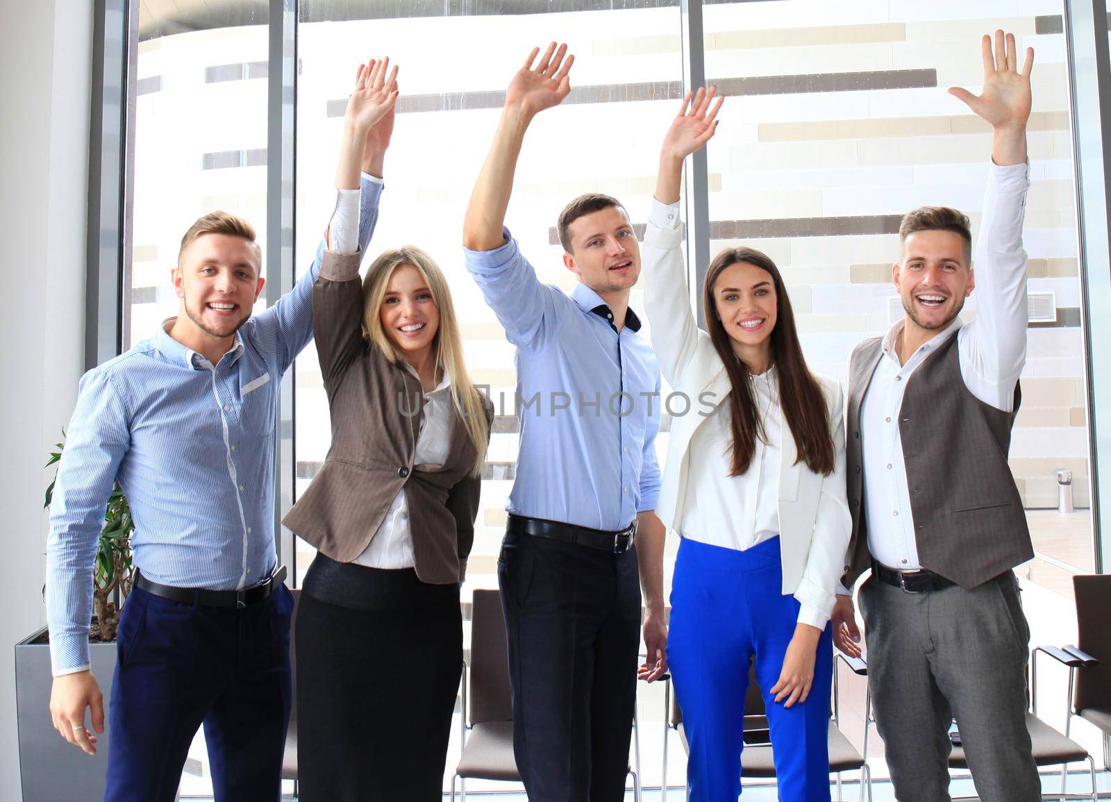 Portrait of successful business group waving hands in office by tsyhun
