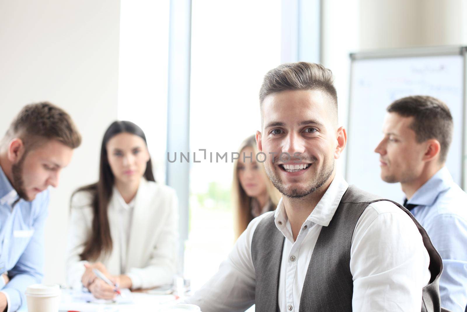 Businessman with colleagues in the background in office.