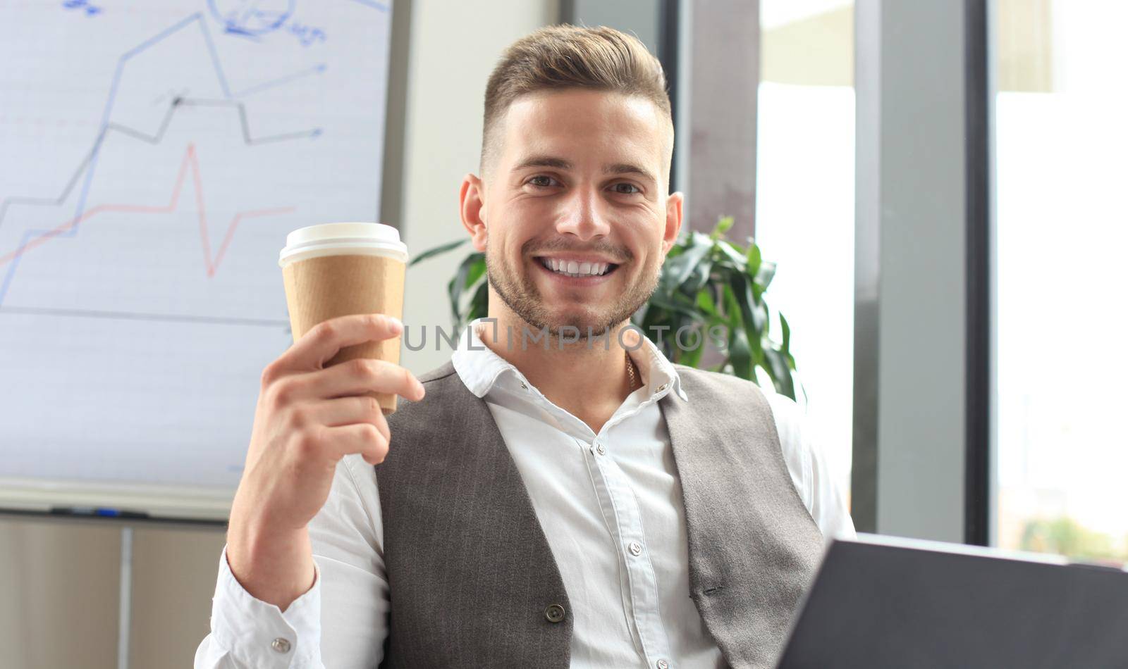 Modern businessman drinking coffee in the office cafe during lunch time and using laptop