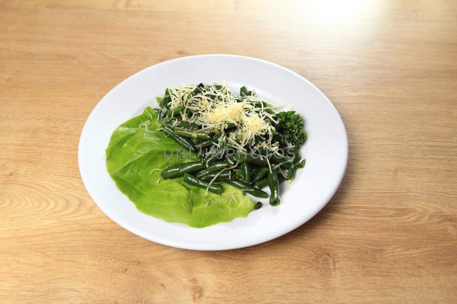 dish of green beans on a white plate on a wooden table