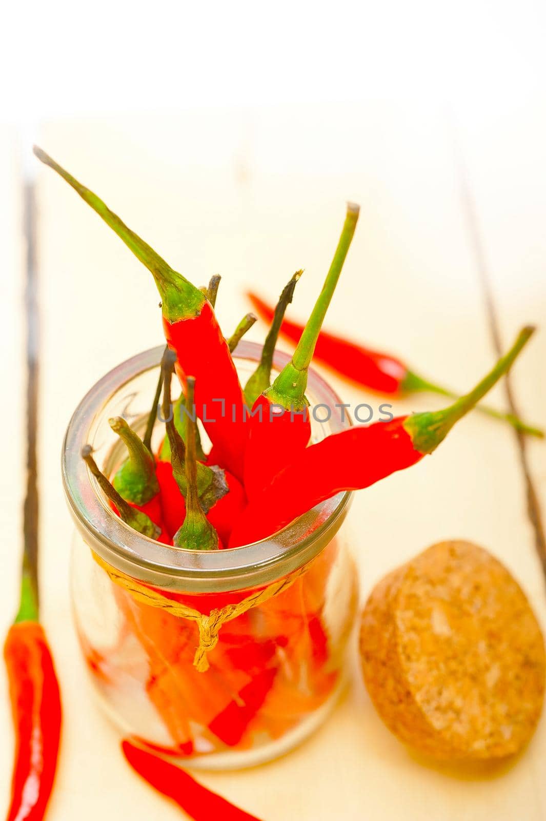 red chili peppers on a glass jar over white wood rustic table