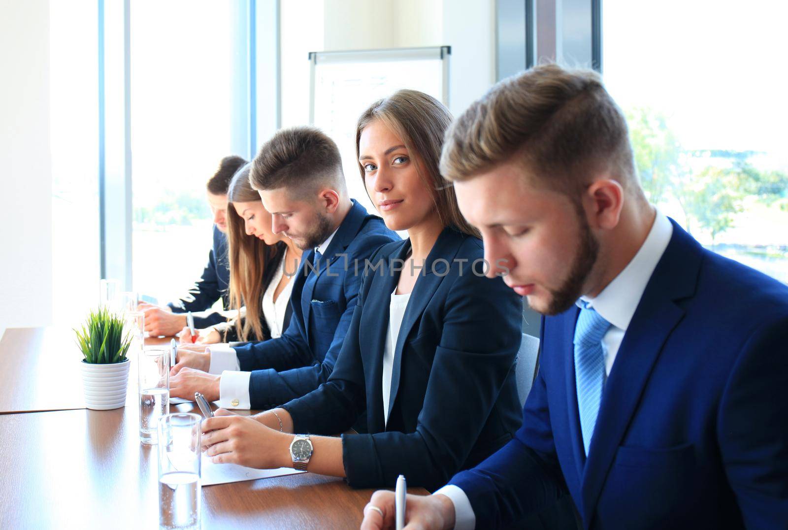 Smiling businesswoman looking at camera at seminar with her colleagues near by by tsyhun