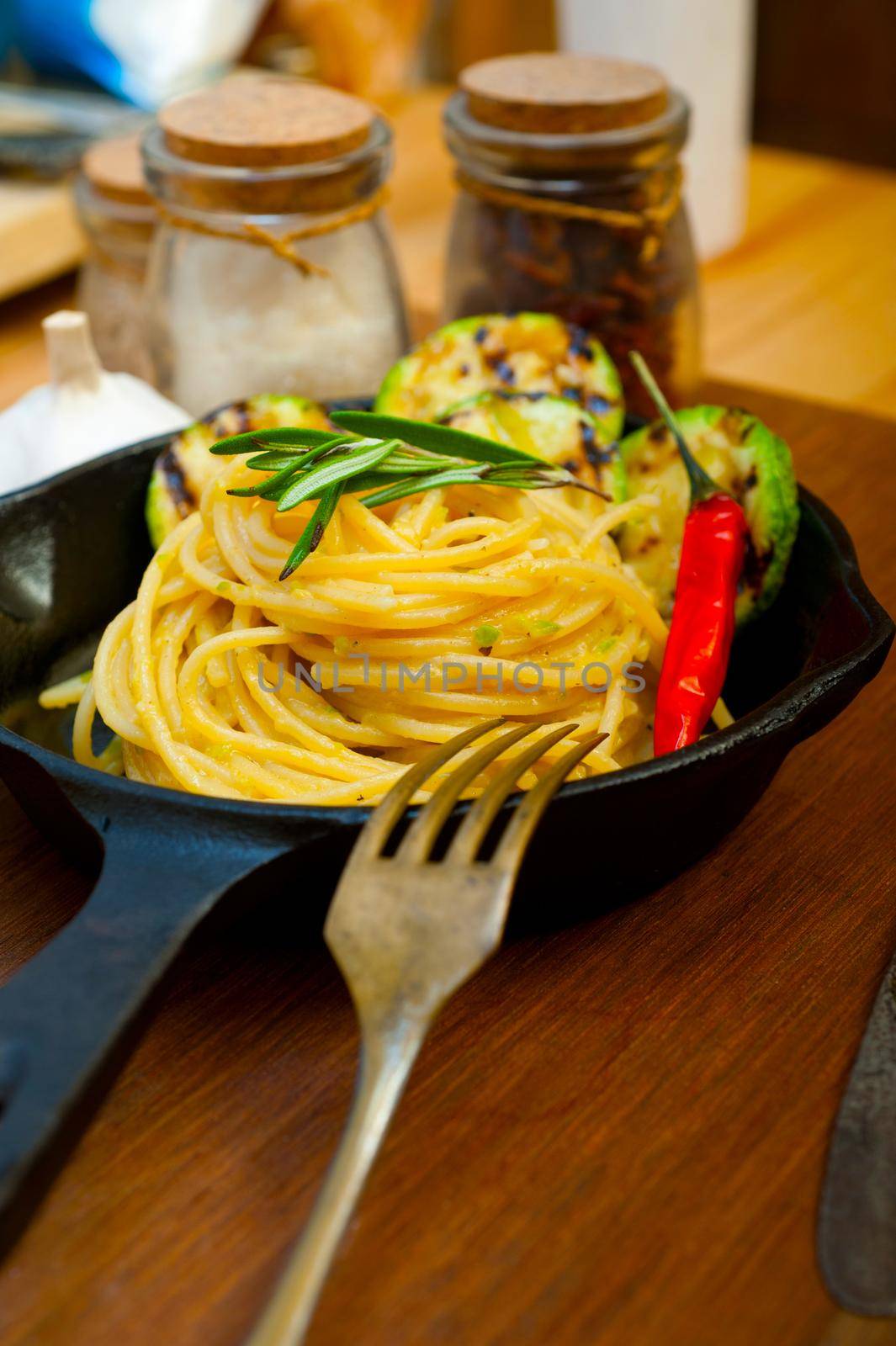 italian spaghetti pasta with zucchini sauce on iron skillet by keko64