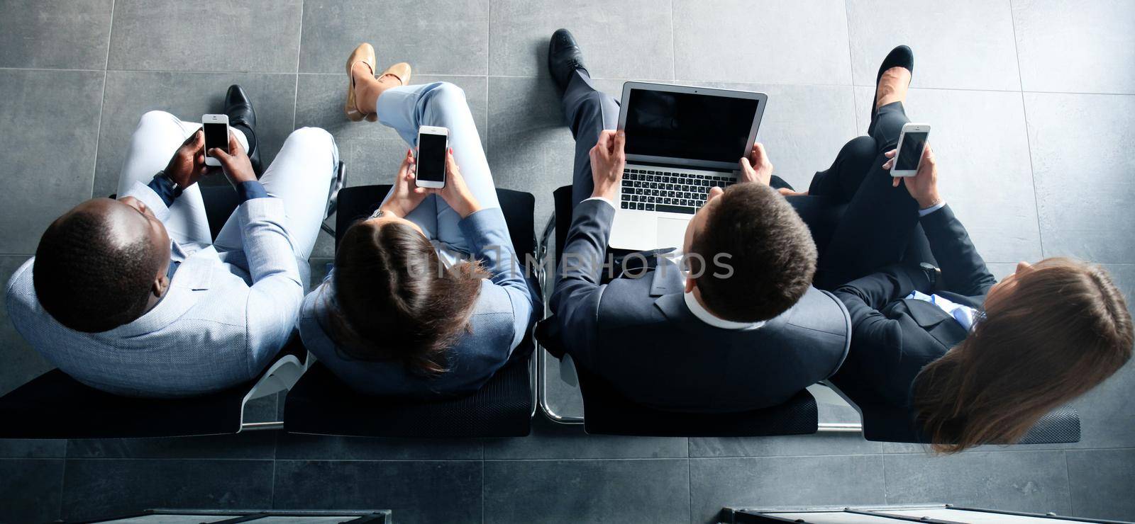 Group of attractive young bussinespeople sitting on the chairs using a laptop, Tablet PC, smart phones, smiling