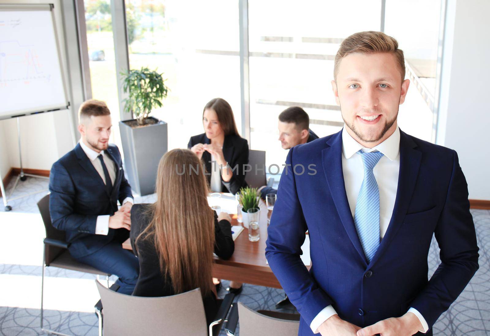 Young businessman standing in office with his collegue on the background by tsyhun