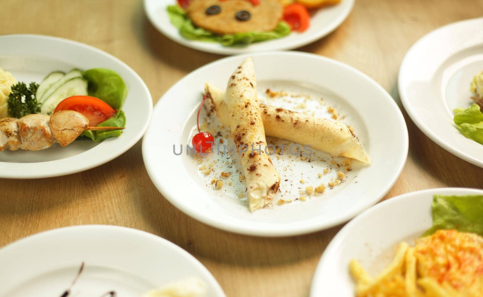 tasty dishes on a table in the children's restaurant, pancakes with a cherry in the middle