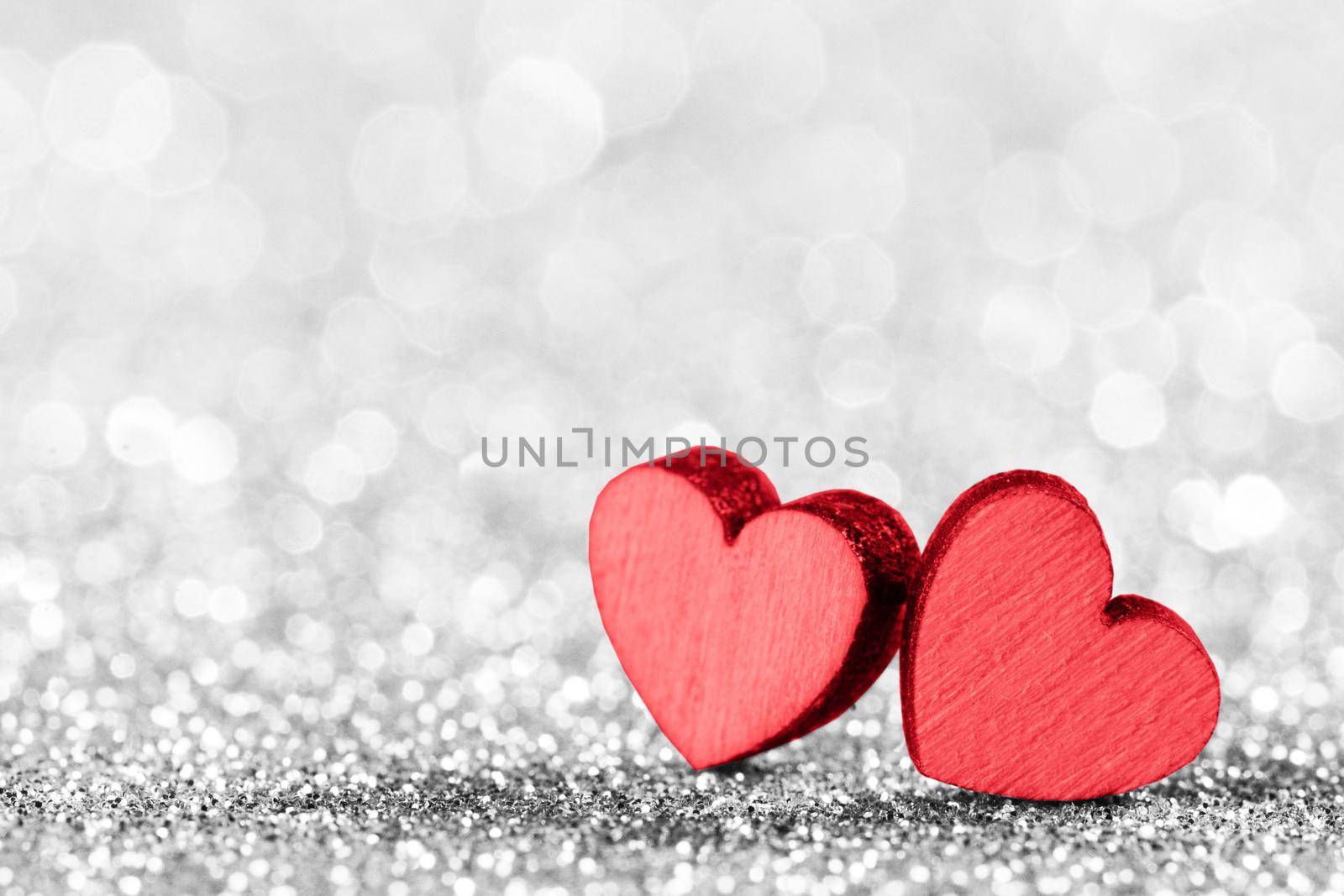 Two red decorative hearts on a glittering silver background with copy space. Valentine's Day card. Design element for romantic greeting card, wedding invitation