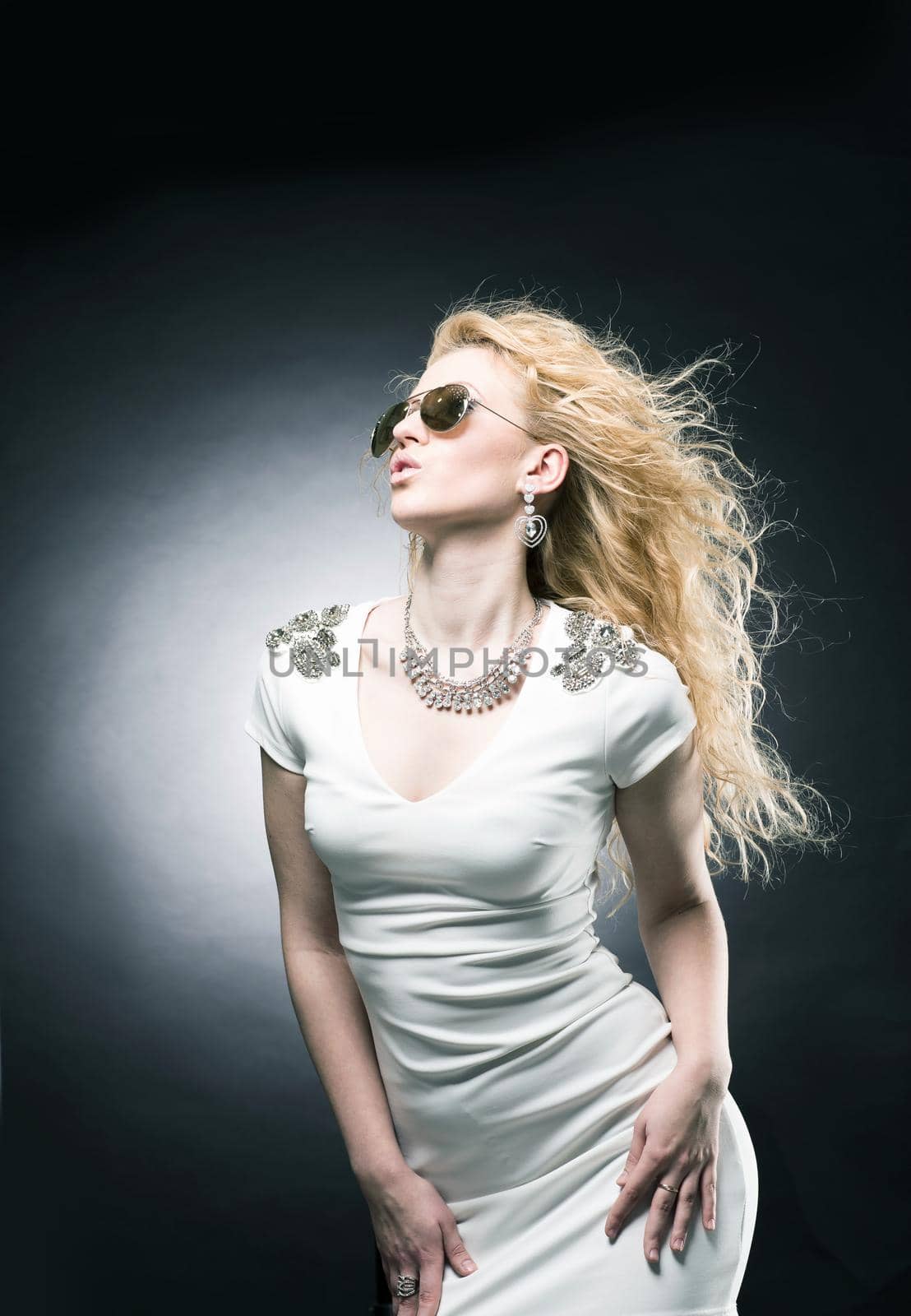 Portrait of a beautiful young blonde woman on a black background in dark glasses looking away