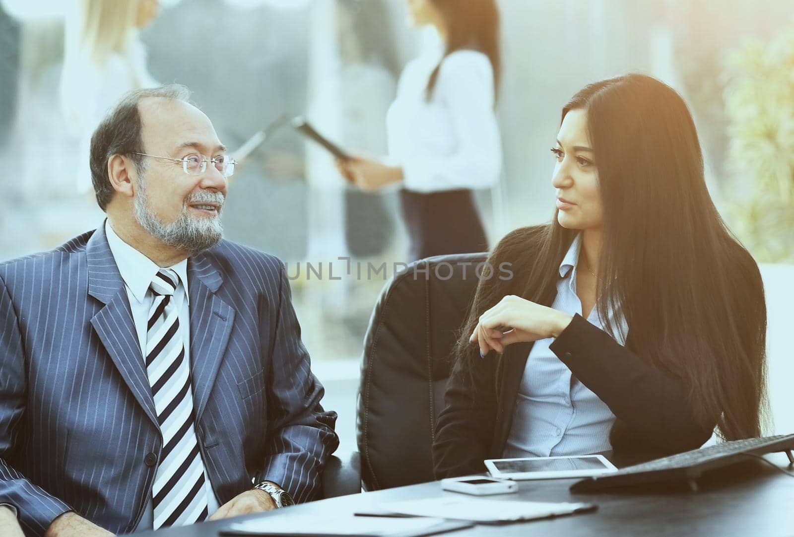 business team is working with financial documents at the office, a discussion between the two partners, the team in the background mode