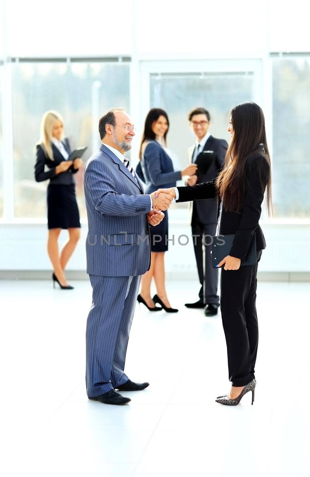 Meeting of two business partners at the presentation, greeting with a handshake on the background of applause team in the background
