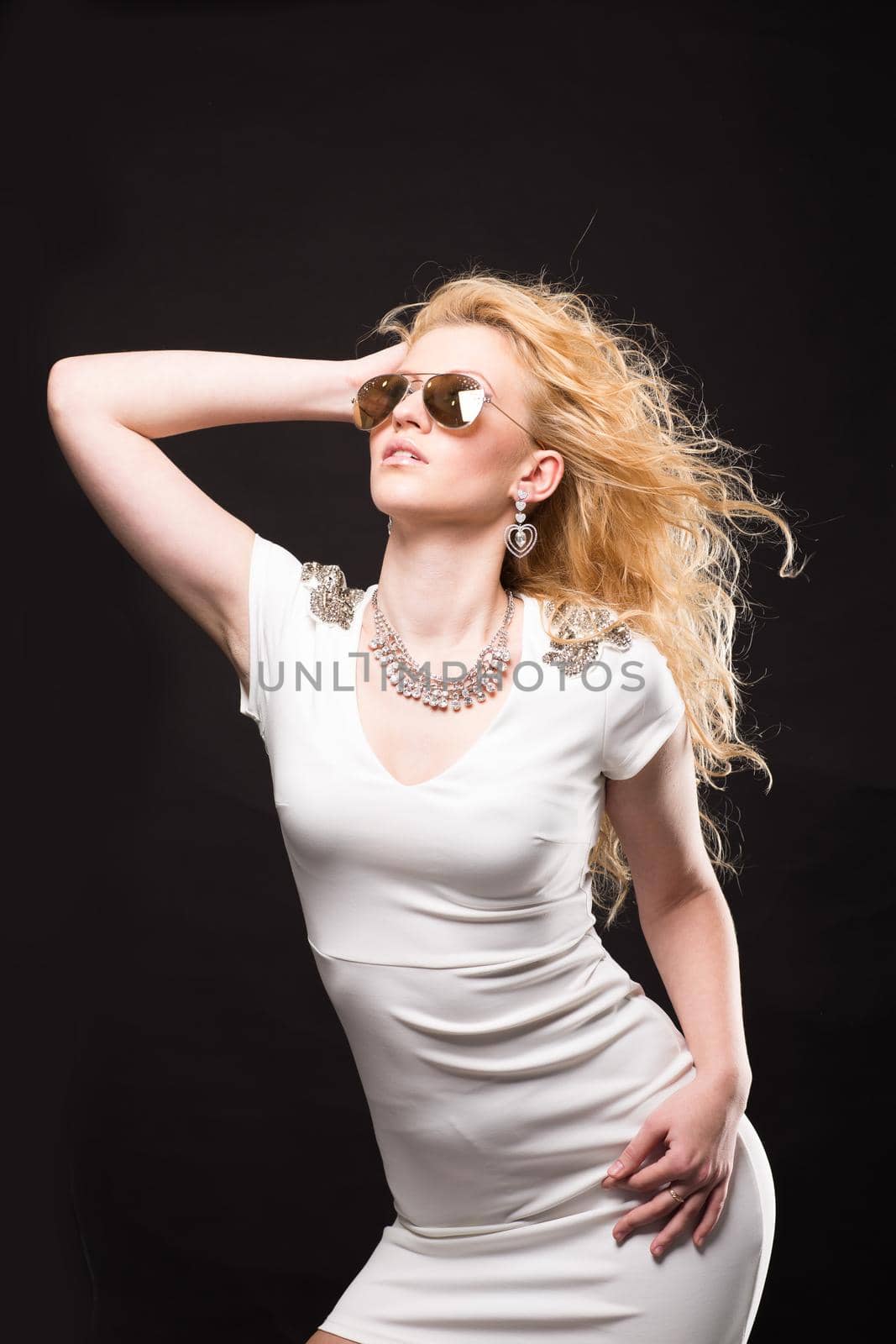 Portrait of a beautiful blonde girl in dark glasses on a black background