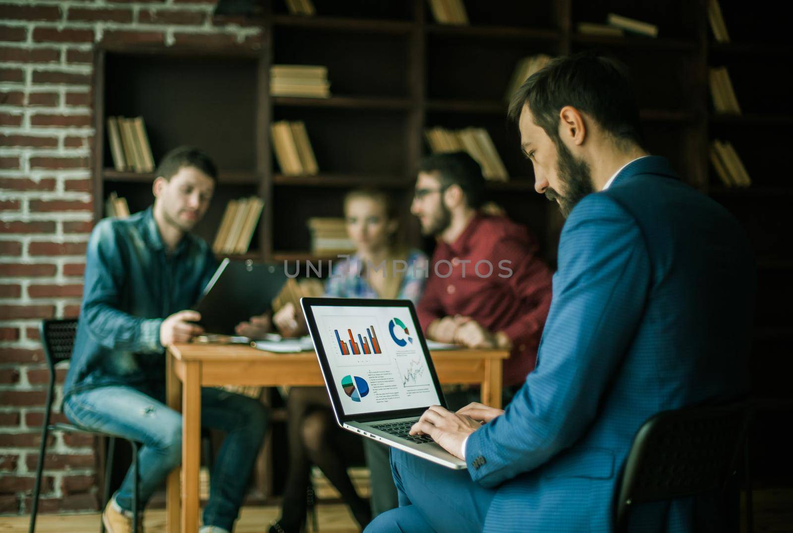 Manager Finance works with the marketing graphics on the laptop on the background of business team workplace in the office