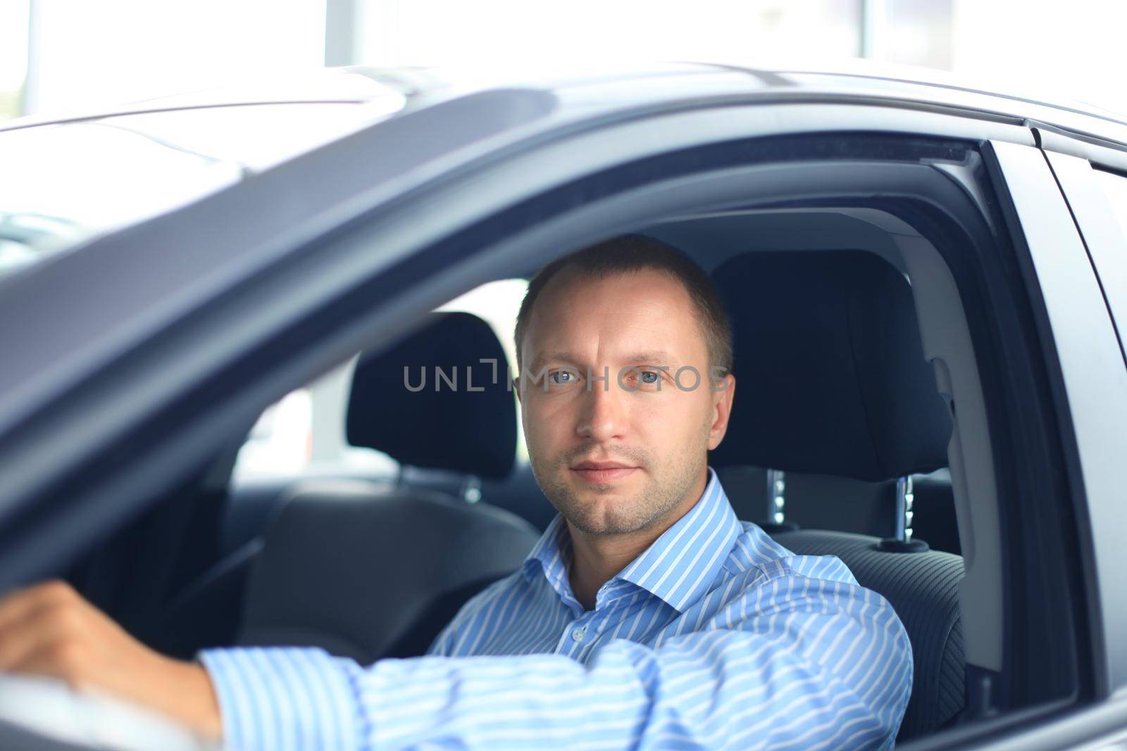 Confident businessman in full suit sitting in the luxe car.