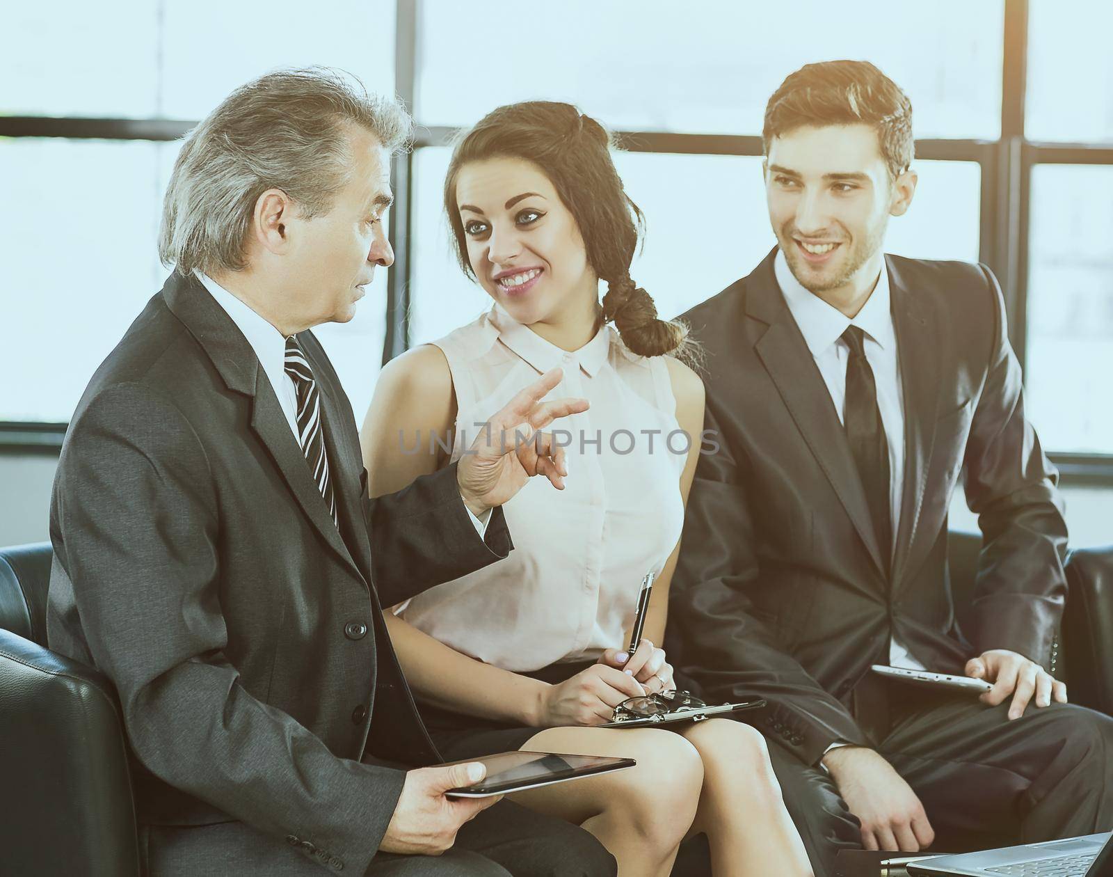 A group of businessmen discussing the policies of the company using a tablet computer in a modern office