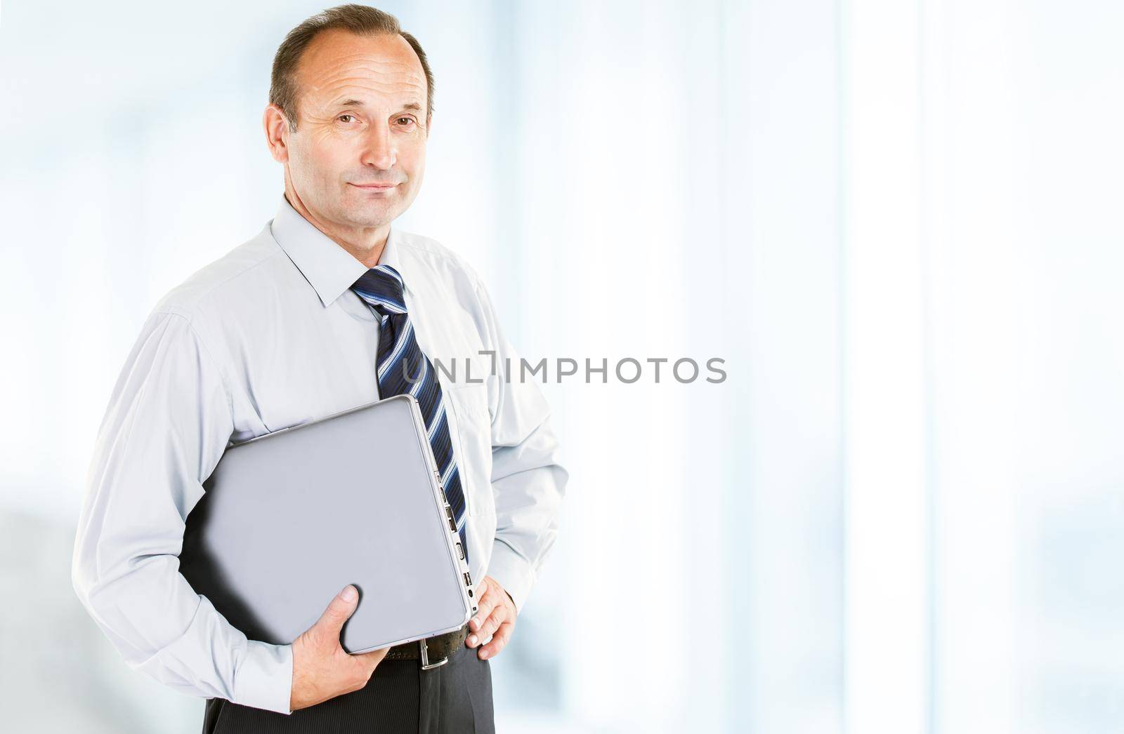 closeup of a business expert in a shirt and tie with a laptop under his arm on a light background. the photo has a empty space for your text