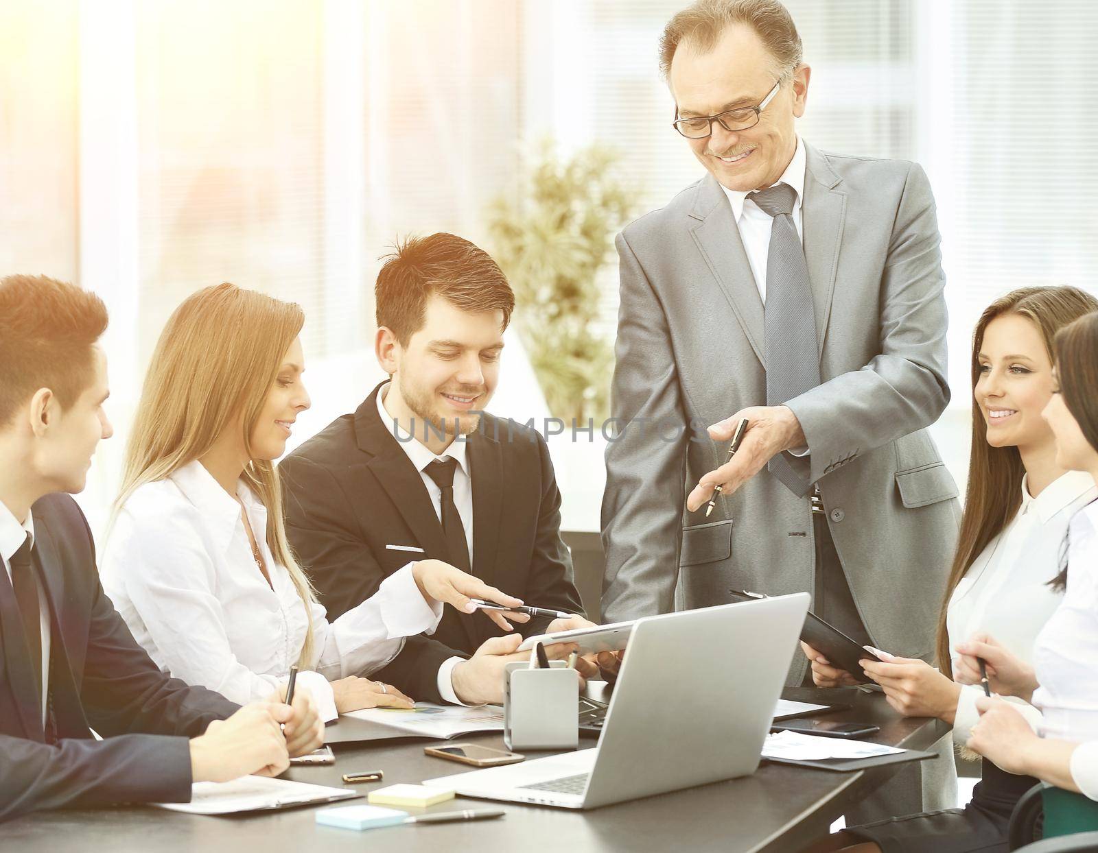 A group of businessmen discussing the policies of the company using a laptop in a modern office