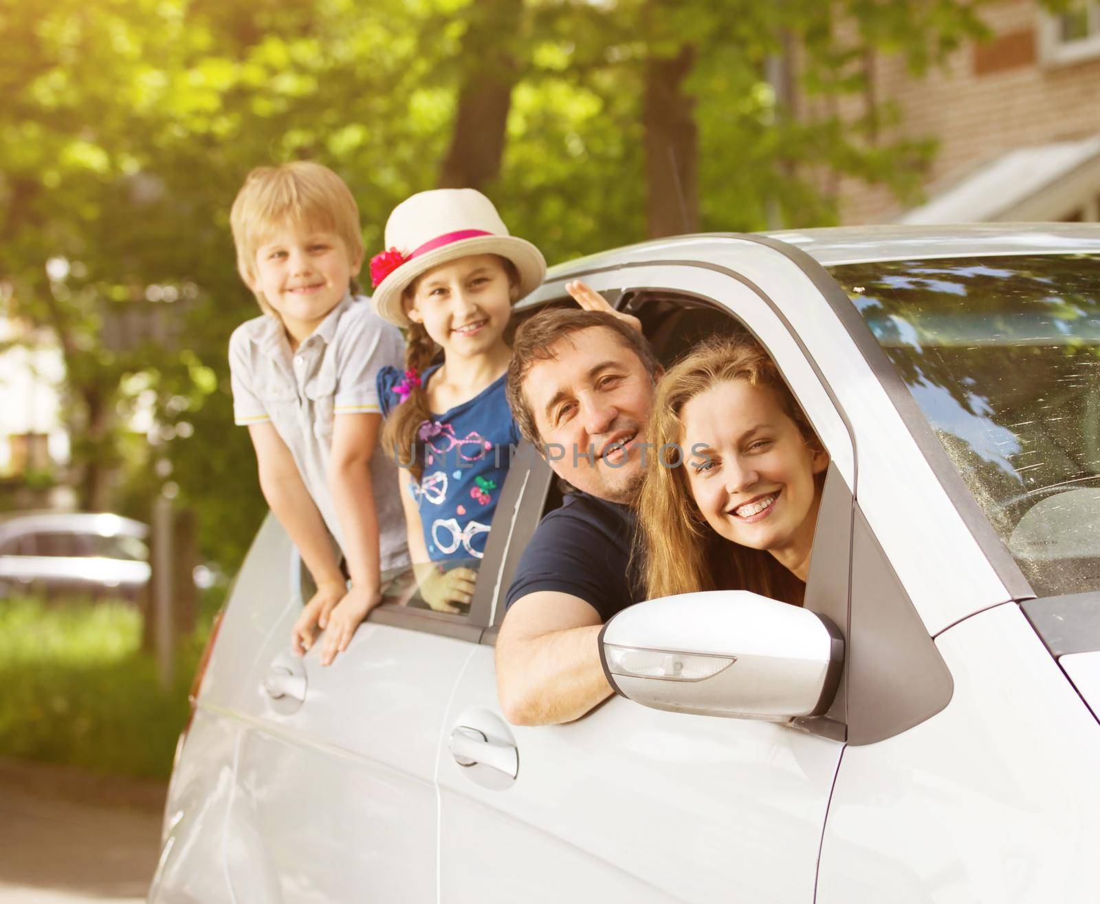 happy family of four people in the car to look out the window and smiling on a sunny day