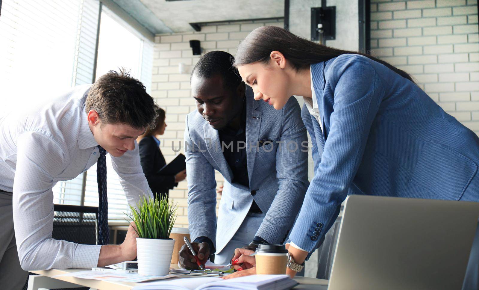 startup business team on meeting in modern bright office interior brainstorming, working on laptop and tablet computer by tsyhun