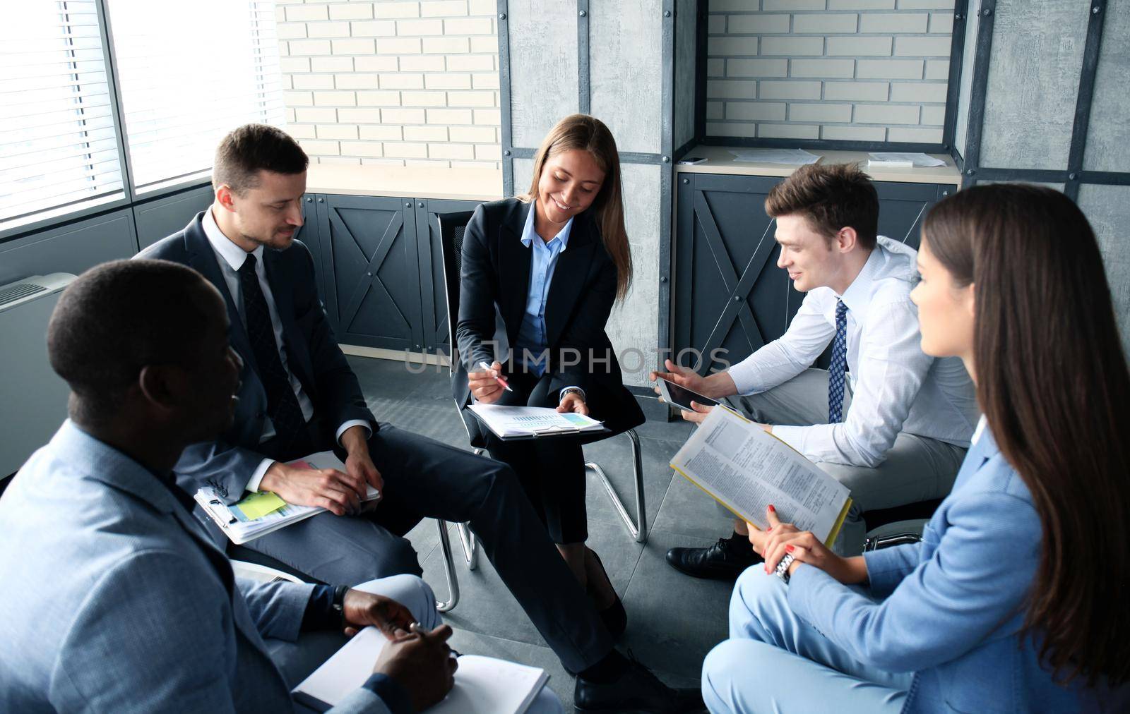 Creative business people meeting in circle of chairs by tsyhun