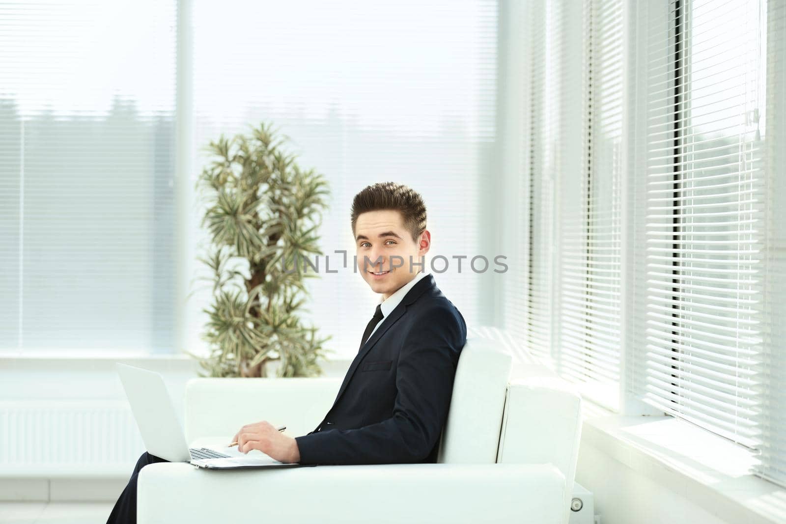 businessman in black business suit sitting behind a Desk in the spacious office