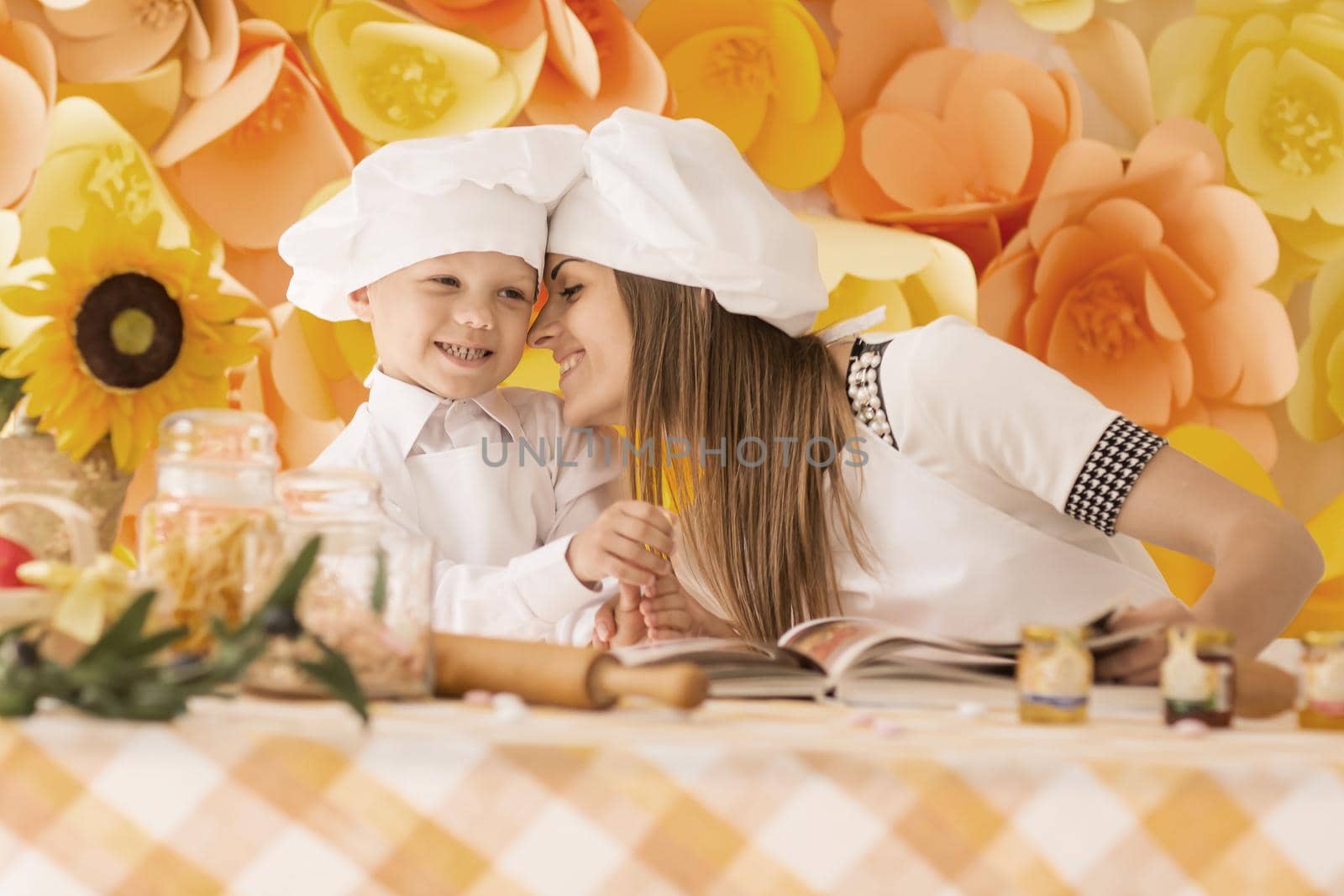 Happy mother and her child in the form of chefs preparing dinner. On a floral background