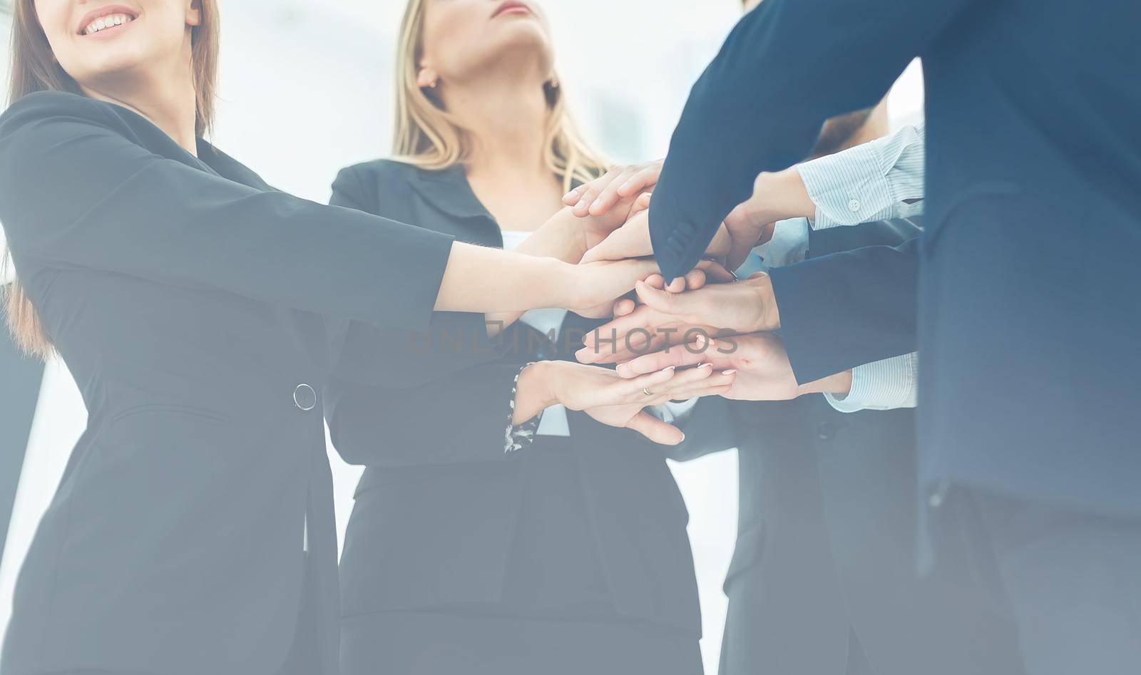 closeup of business team standing in a circle shaking hands with each other.