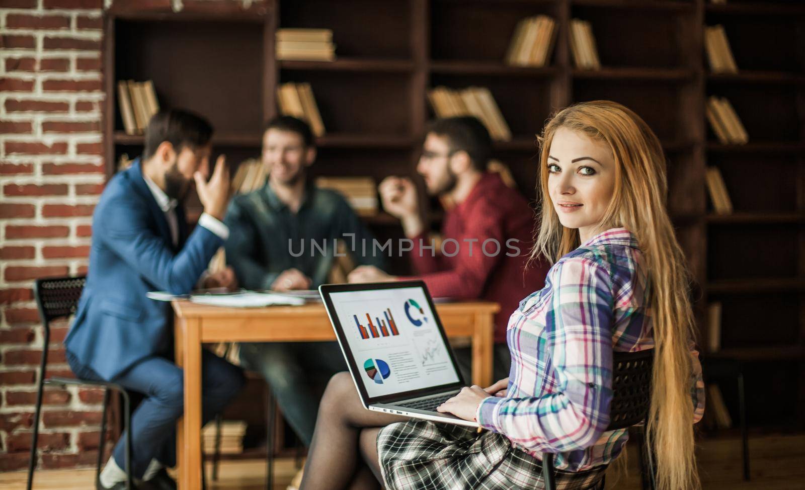 sales Manager working on laptop with a marketing report on the background of business team in a modern office