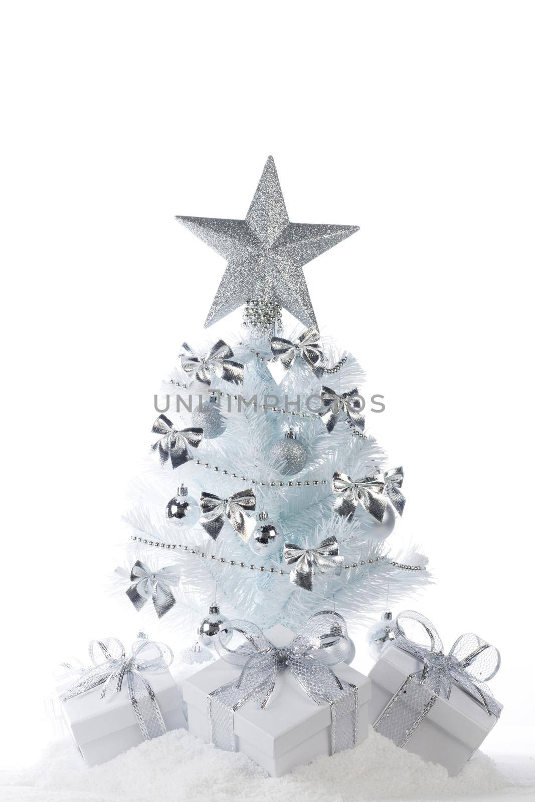 White christmas tree with silver decorations and gifts isolated on snow on white background