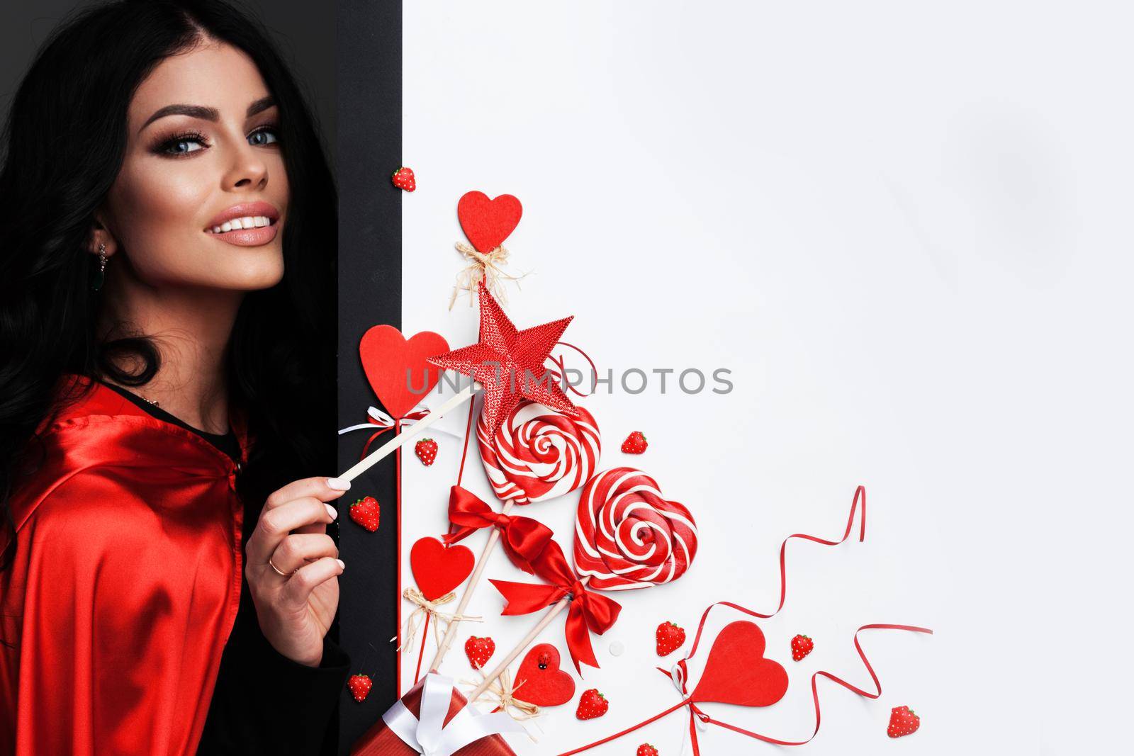 Woman with magic wand near Valentines day decoration and heart shaped lollipops isolated on white background