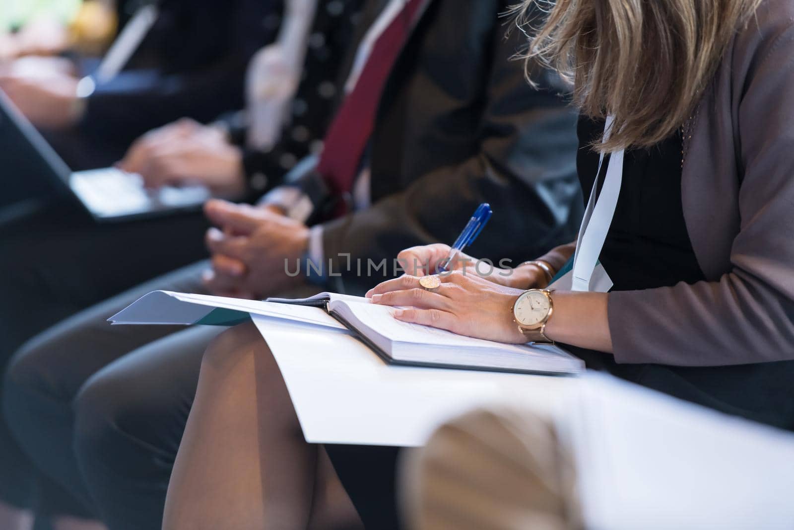 closeup shot of business people hands using pen while taking notes on education training during business seminar at modern conference room