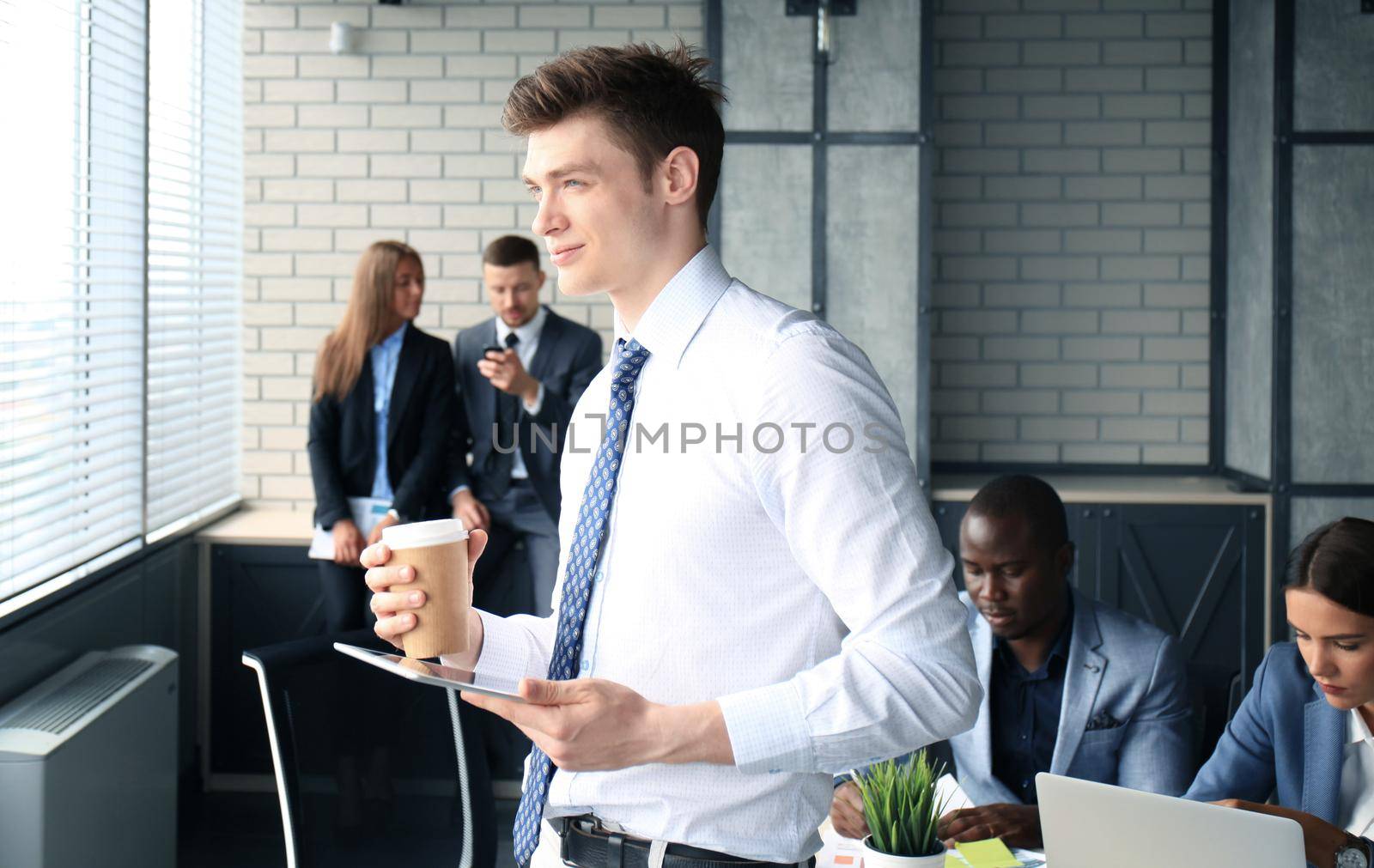 Young businessman standing in office with his collegue on the background