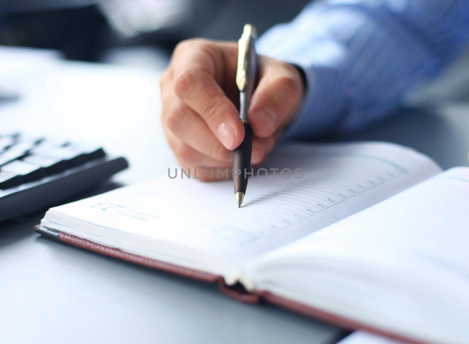 Businessman sitting at office desk signing a contract with shallow focus on signature.