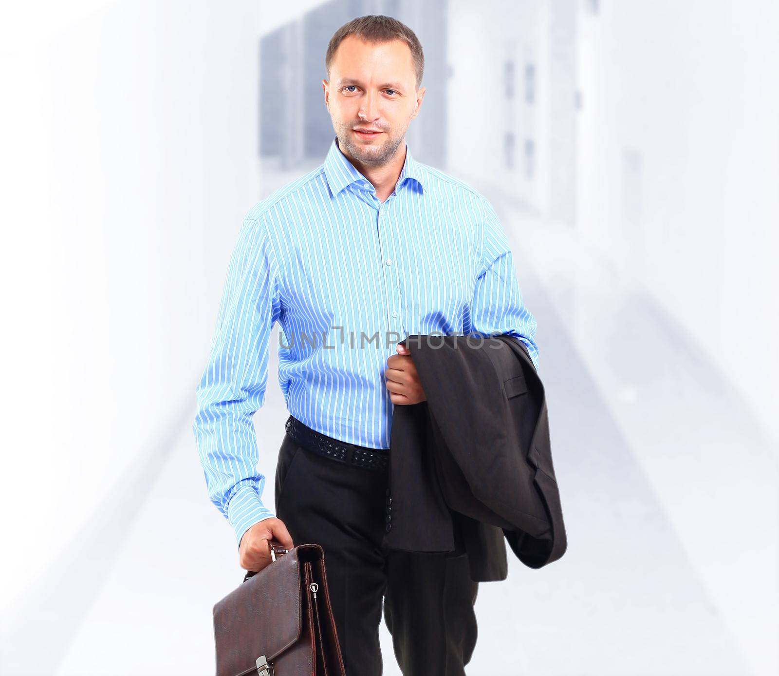 Portrait of a happy young business man carrying a suitcase by tsyhun