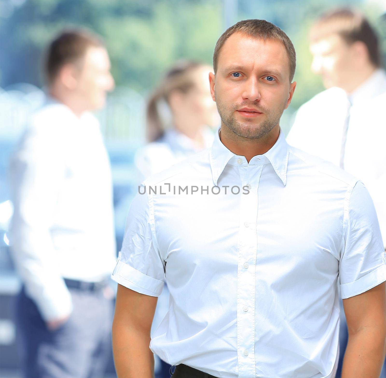 Handsome happy business man with colleagues at the back