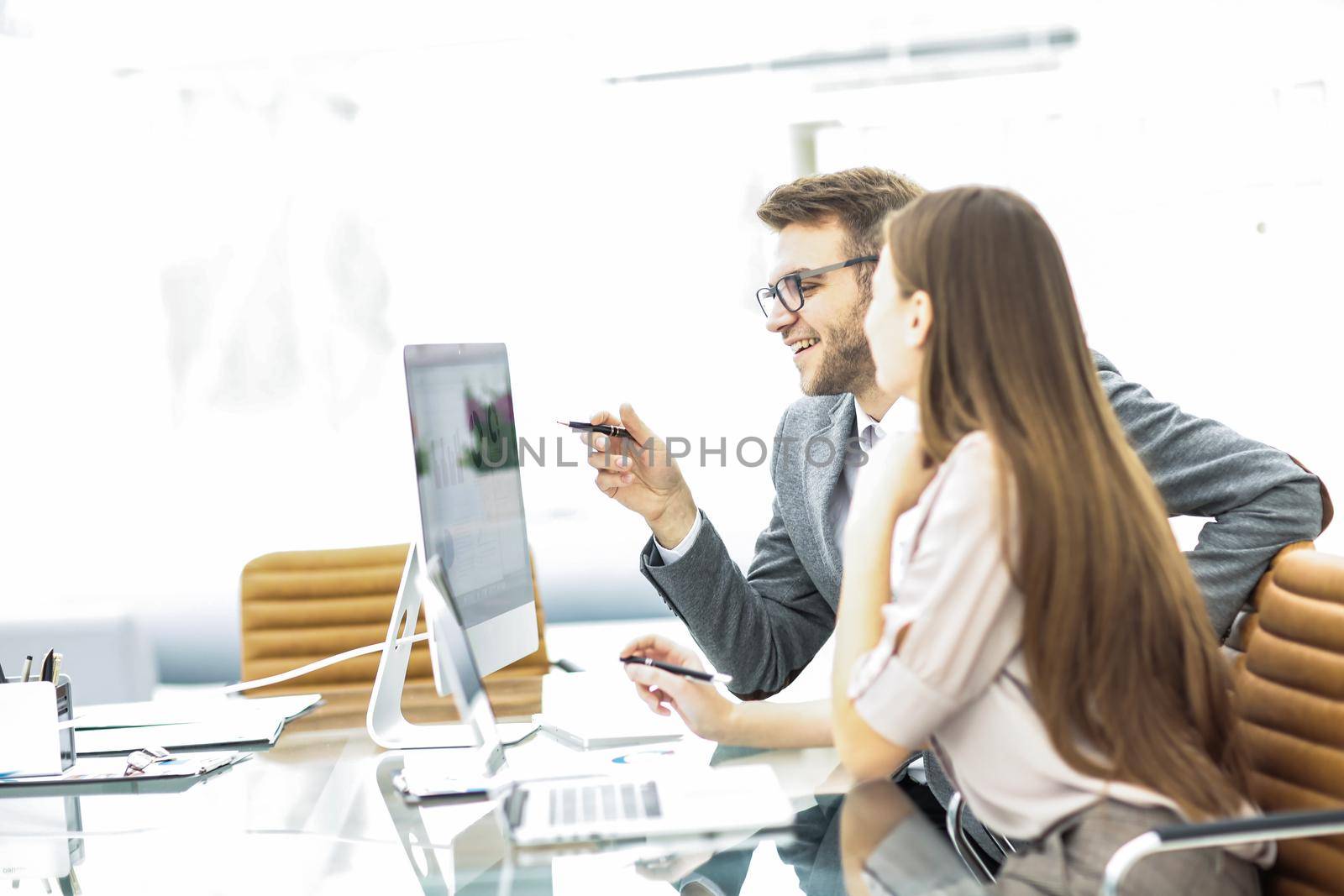Manager and accountant are sitting and discussing financial charts with profits and expenditures of the company in the workplace in the office.the photo has a empty space for your text