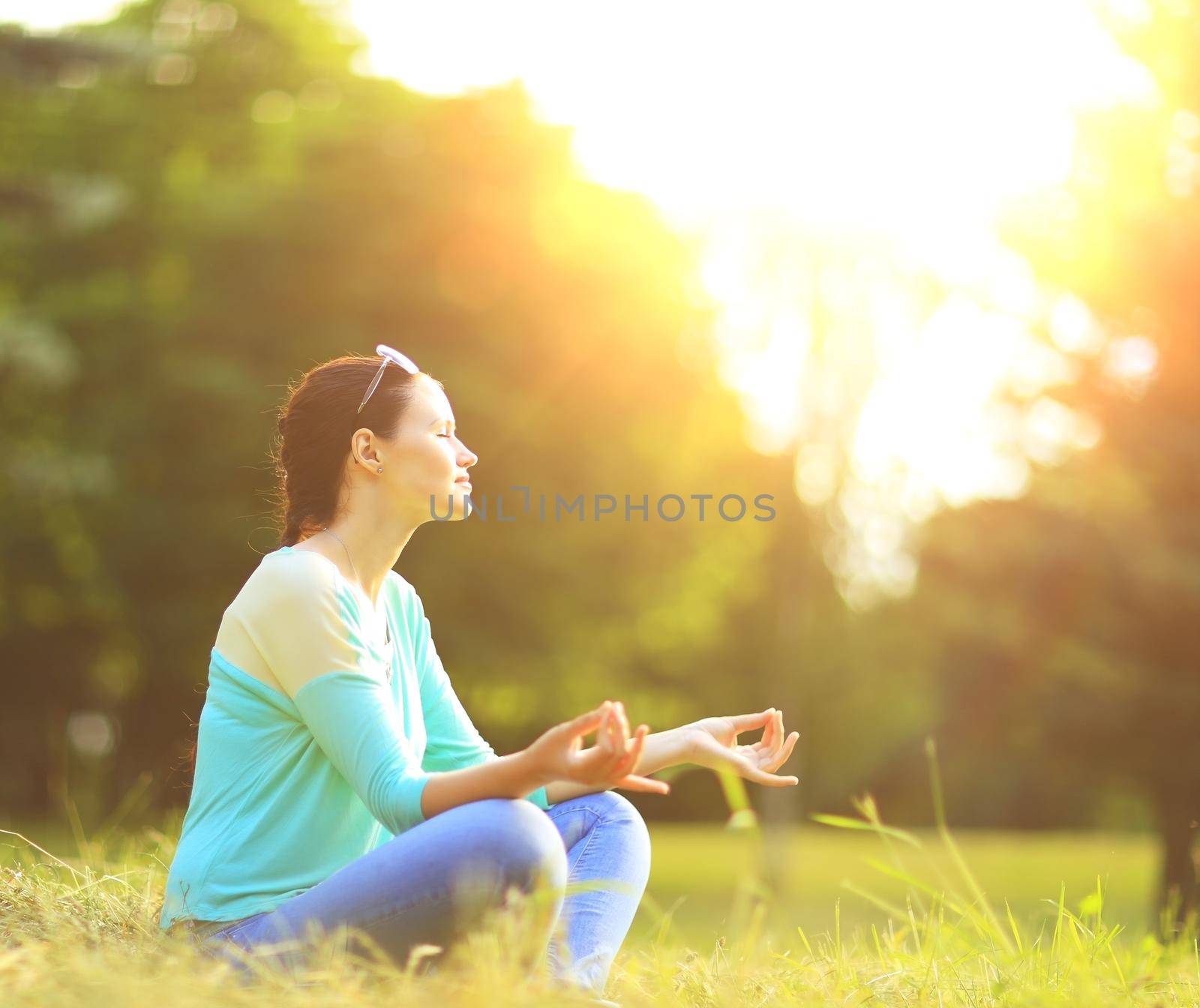 Attractive young woman in lotus position in the park by SmartPhotoLab