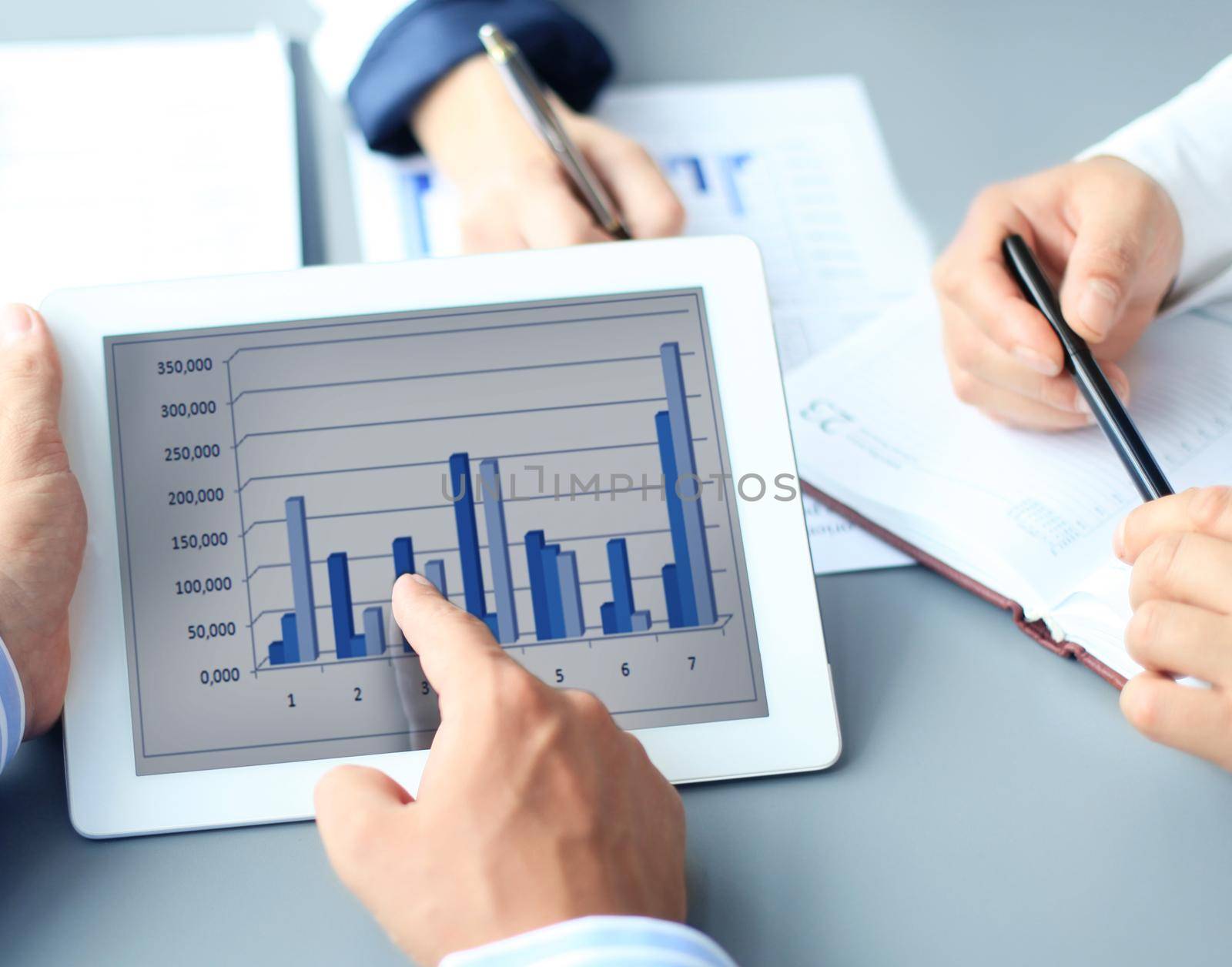 Image of human hand pointing at touchscreen in working environment at meeting