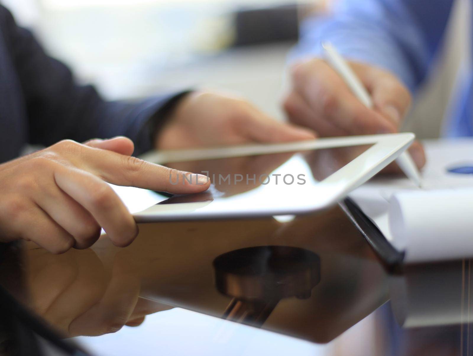 Image of human hand pointing at touchscreen in working environment at meeting