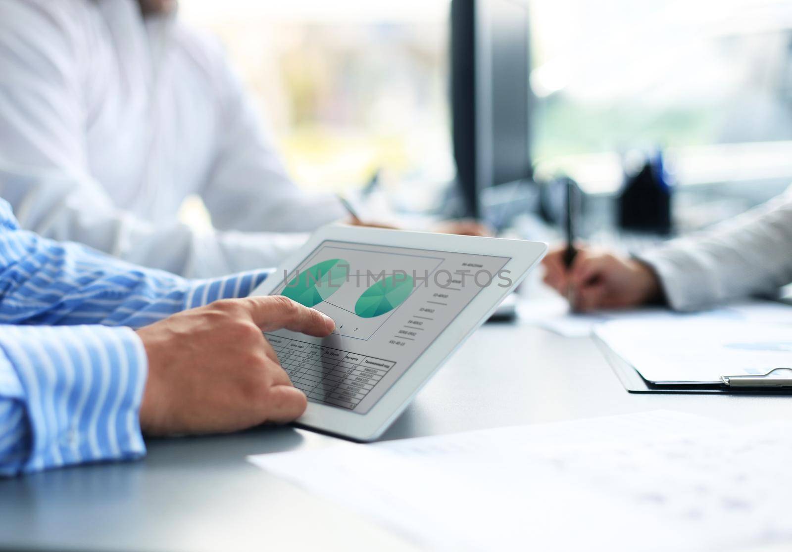 Image of human hand pointing at touchscreen in working environment at meeting